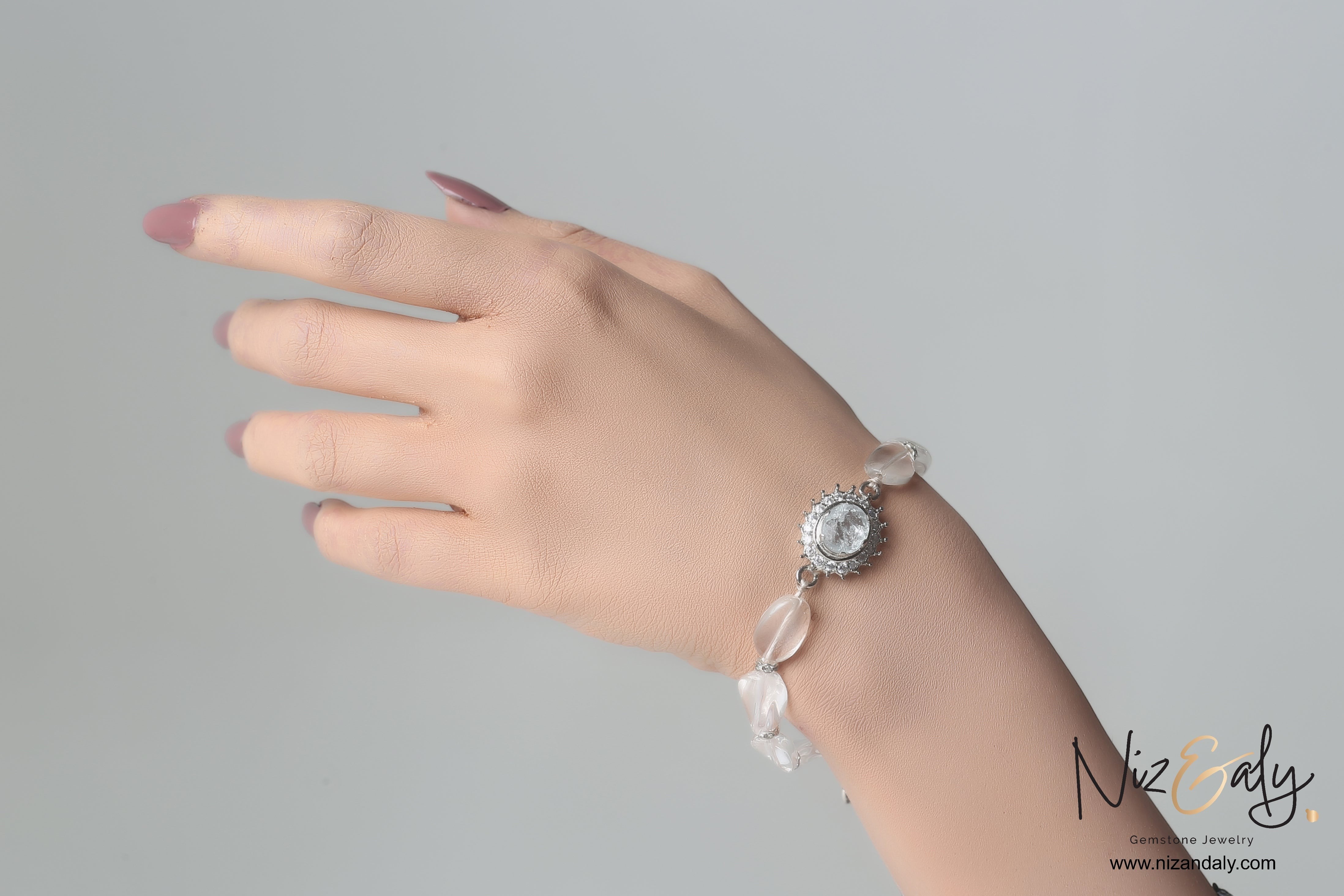 Niz & Aly clear quartz beaded bracelet with a central crystal charm worn on a woman's wrist