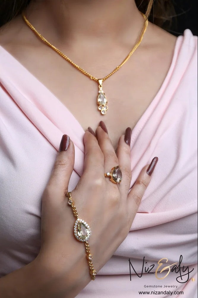 Niz & Aly gold-plated 925 silver jewelry set featuring teardrop clear quartz necklace, bracelet, and ring on a model.