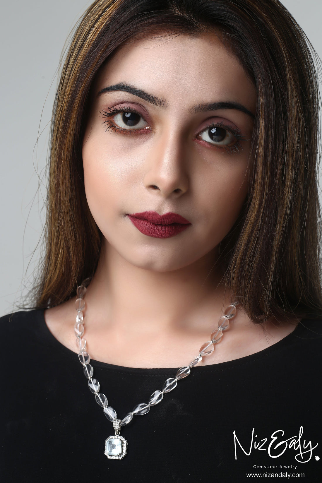 Niz & Aly clear quartz pendant necklace with icy quartz beads worn by a woman with dark lipstick.