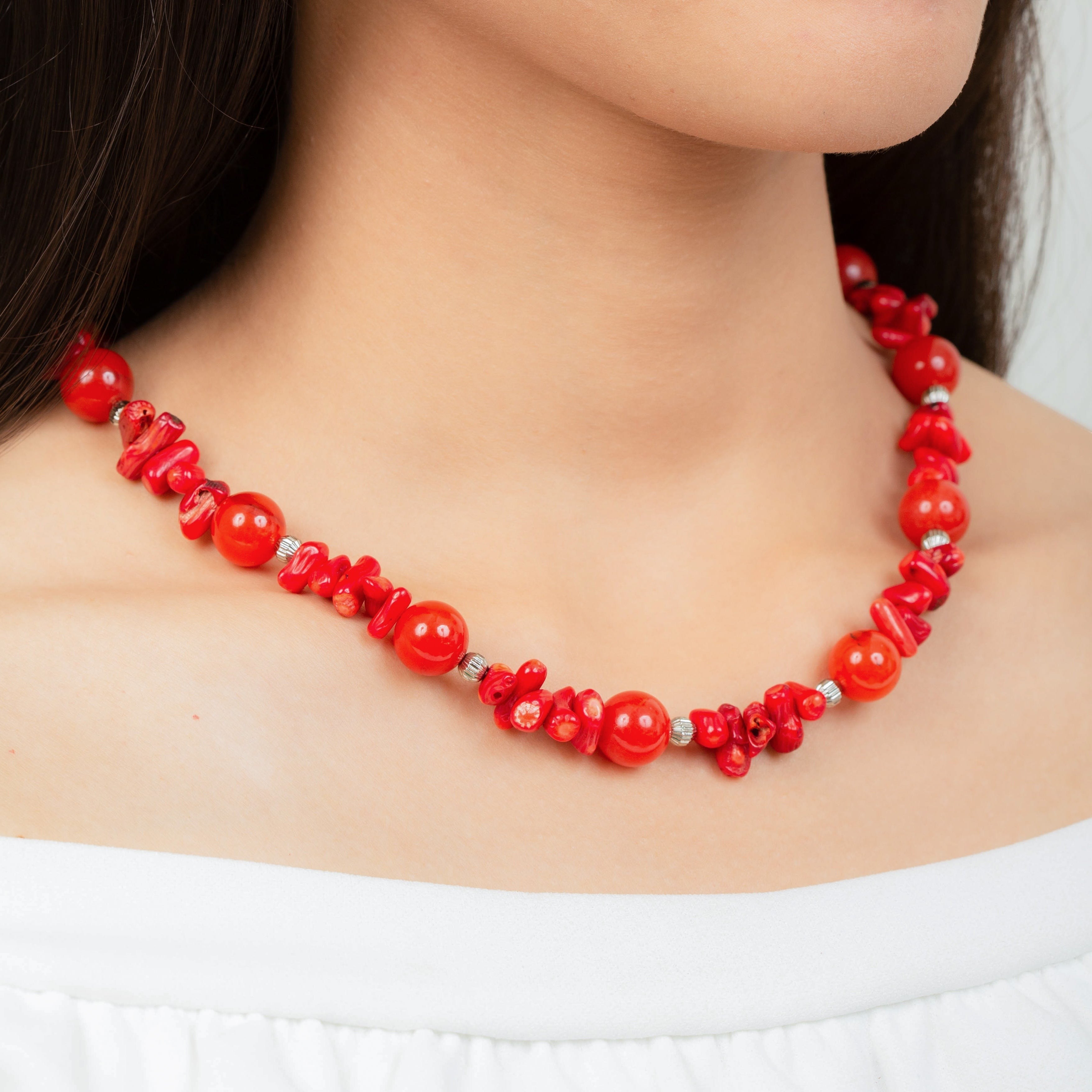 Niz & Aly coral and carnelian bead necklace worn on a model, featuring vibrant red natural gemstone beads.