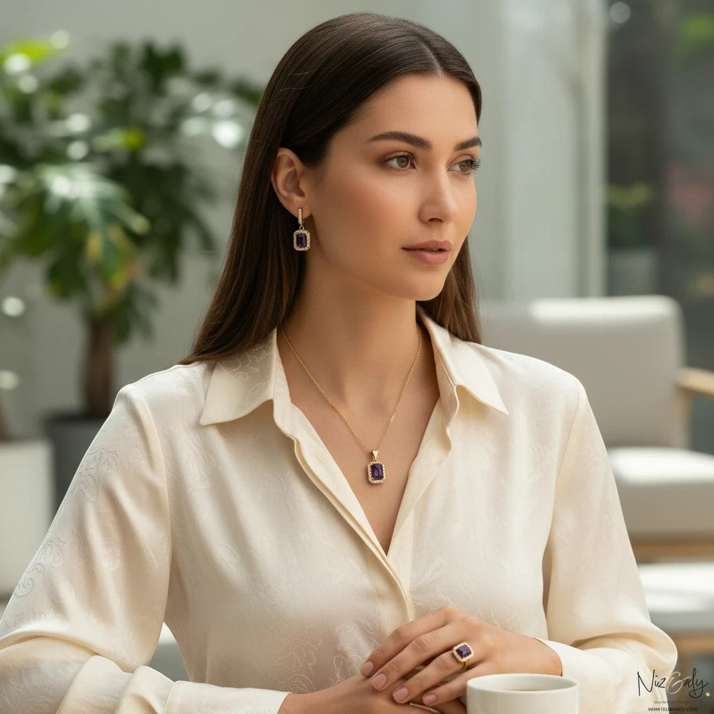 Niz & Aly cushion cut dark amethyst drop pendant necklace and matching earrings worn by a woman in a cream blouse.
