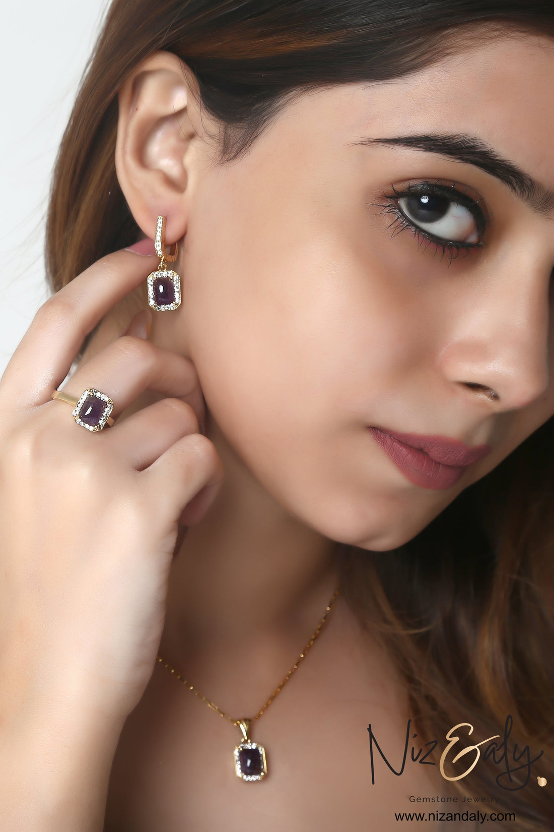Niz & Aly cushion cut dark amethyst pendant, ring, and earring set with diamond accents on a model