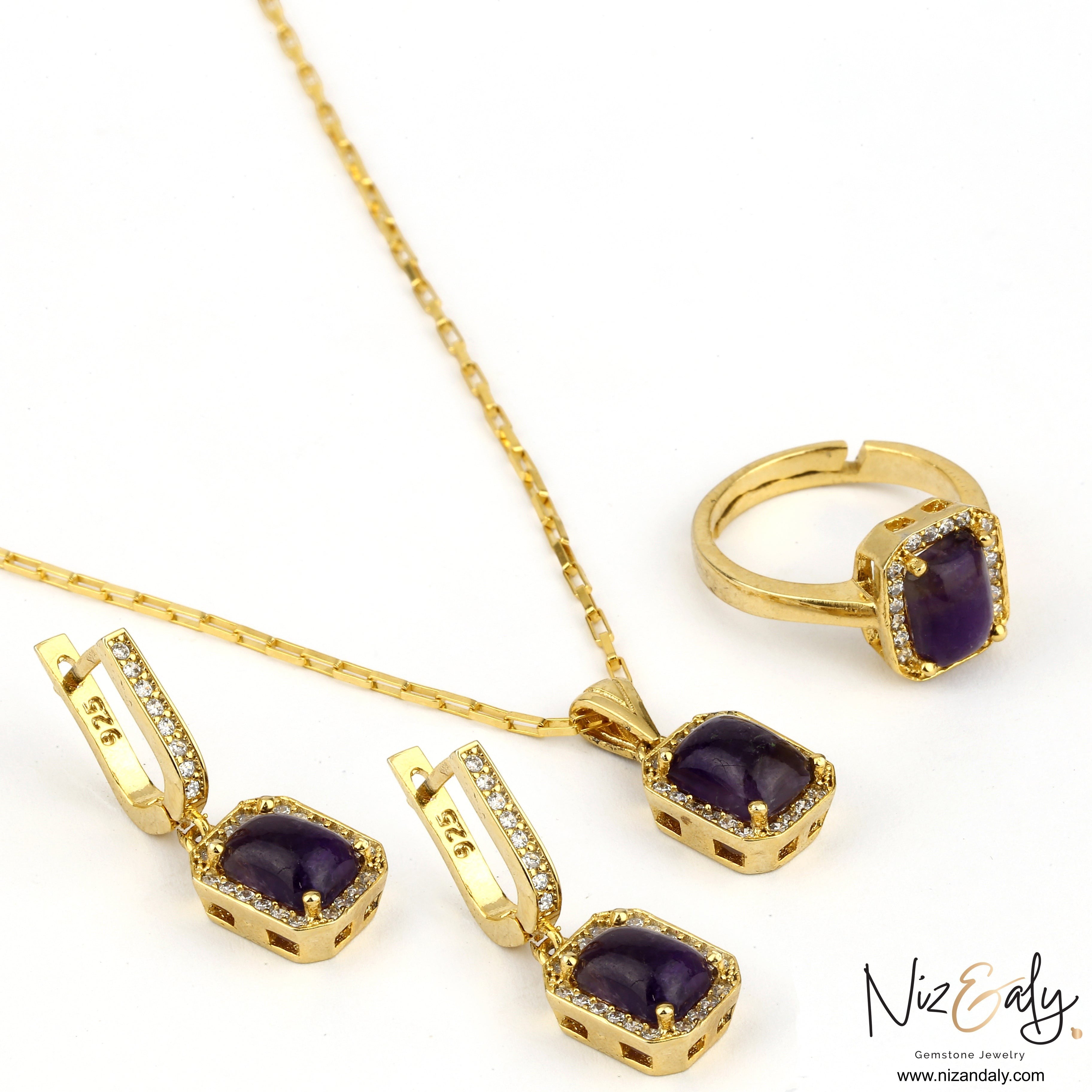 Niz & Aly cushion cut dark amethyst pendant, earrings, and ring set in gold with sparkling stone accents.