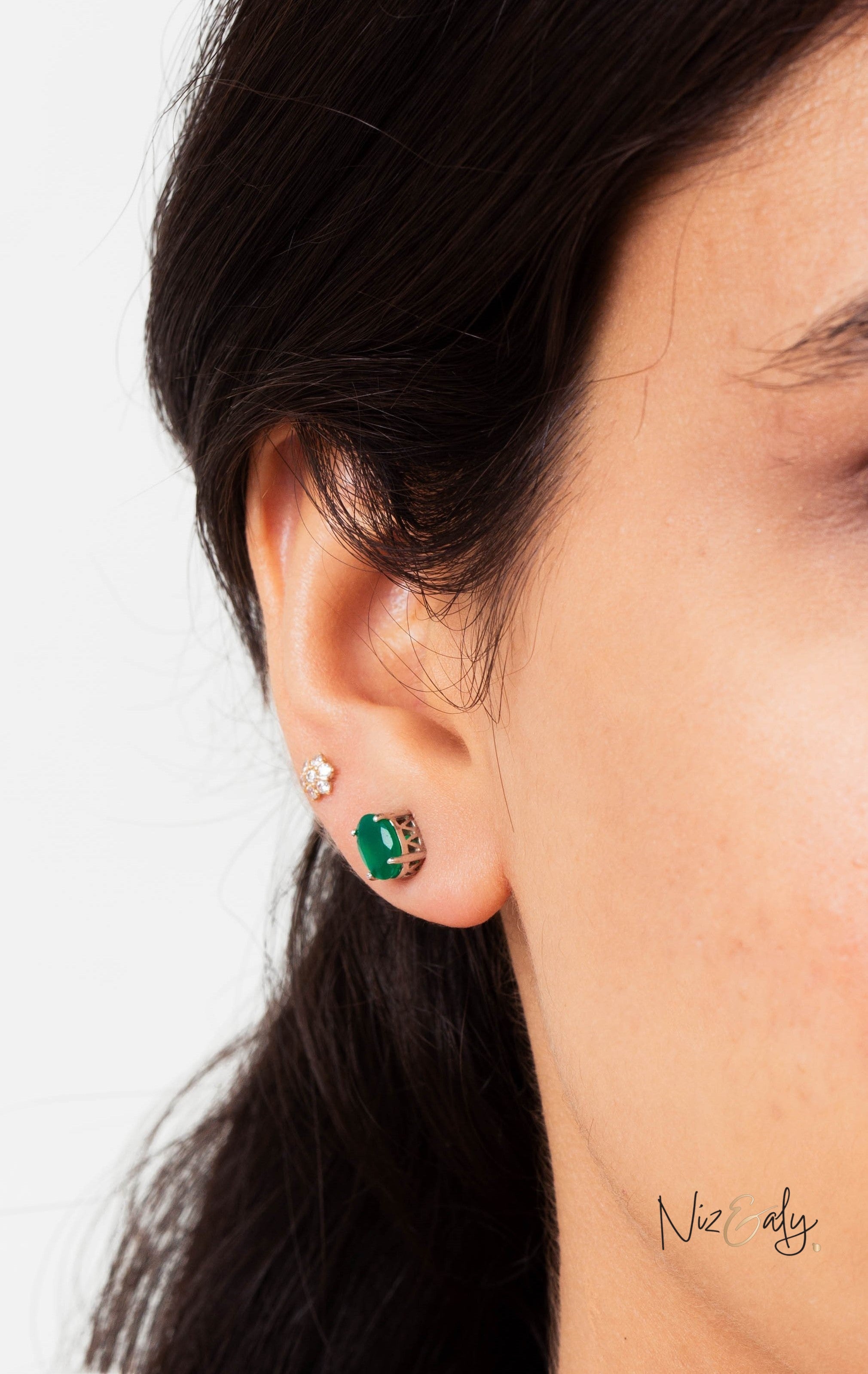 Niz & Aly dainty emerald ear stud worn on a model, featuring a vibrant green gemstone in a refined metal setting.