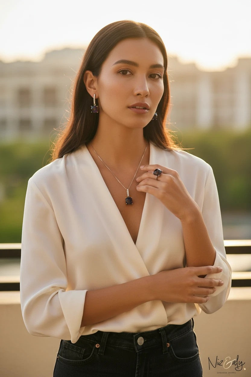 Niz & Aly square dark amethyst pendant necklace, earrings, and ring set worn by a woman in a white blouse.