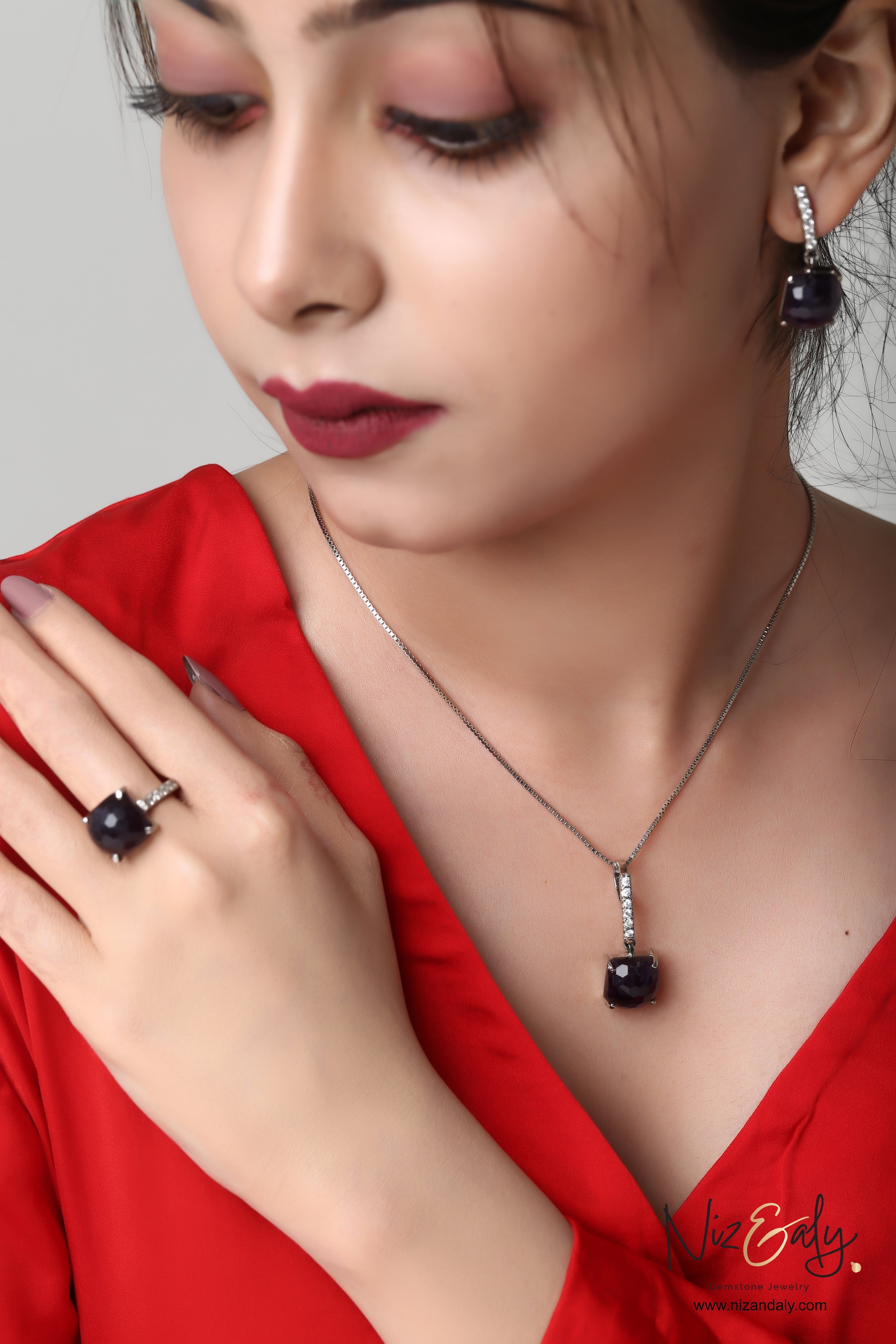 Niz & Aly square dark amethyst pendant set with matching earrings and ring worn by a woman in a red top