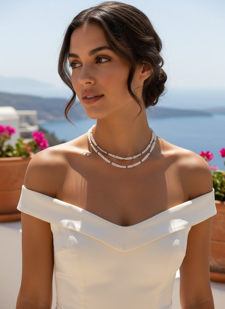 Niz & Aly dainty double-strand milky quartz necklace worn by a woman in a white off-shoulder dress outdoors.