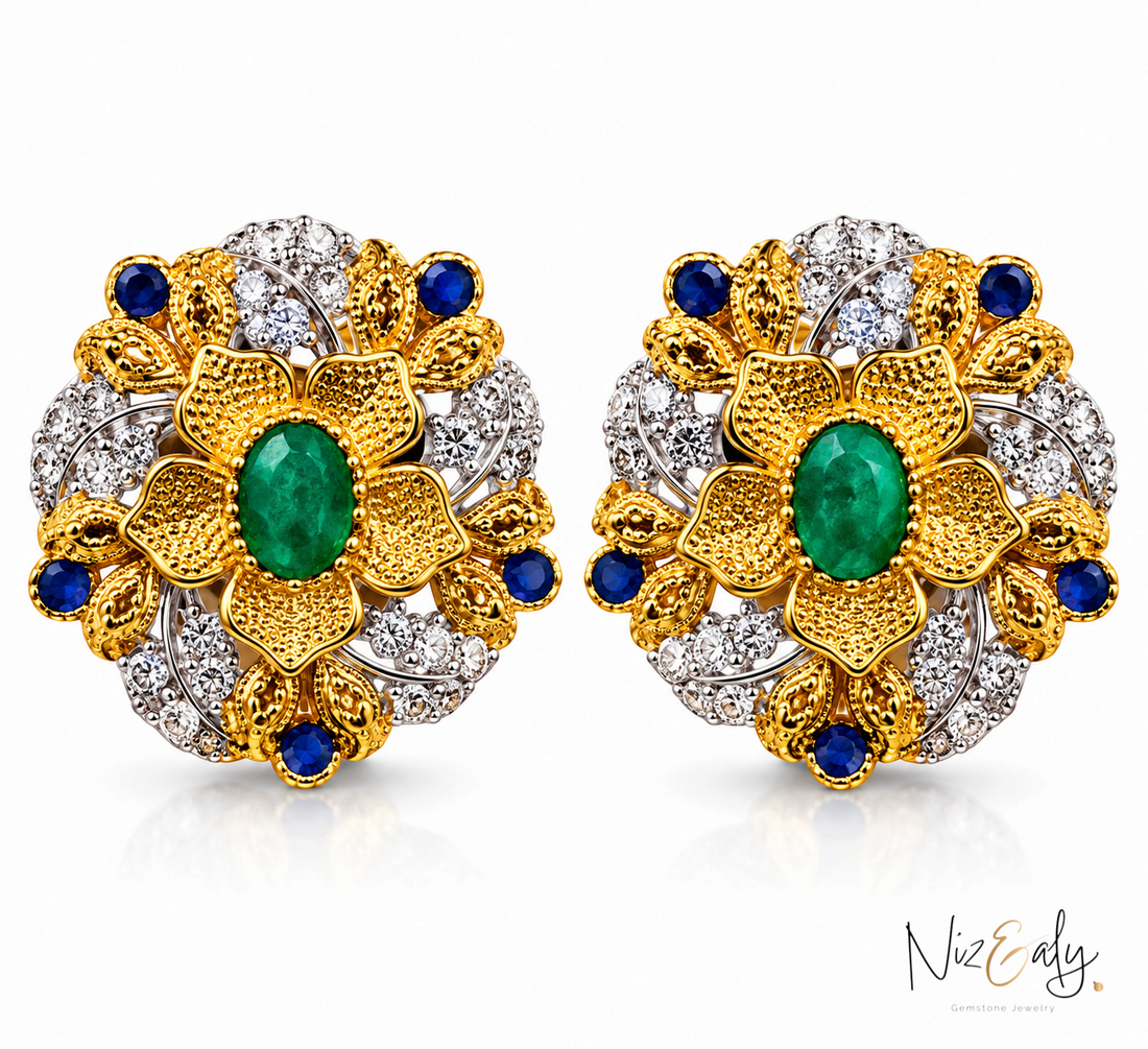 Niz & Aly floral stud earrings featuring a central emerald in a bezel setting, accented with diamonds and sapphires.