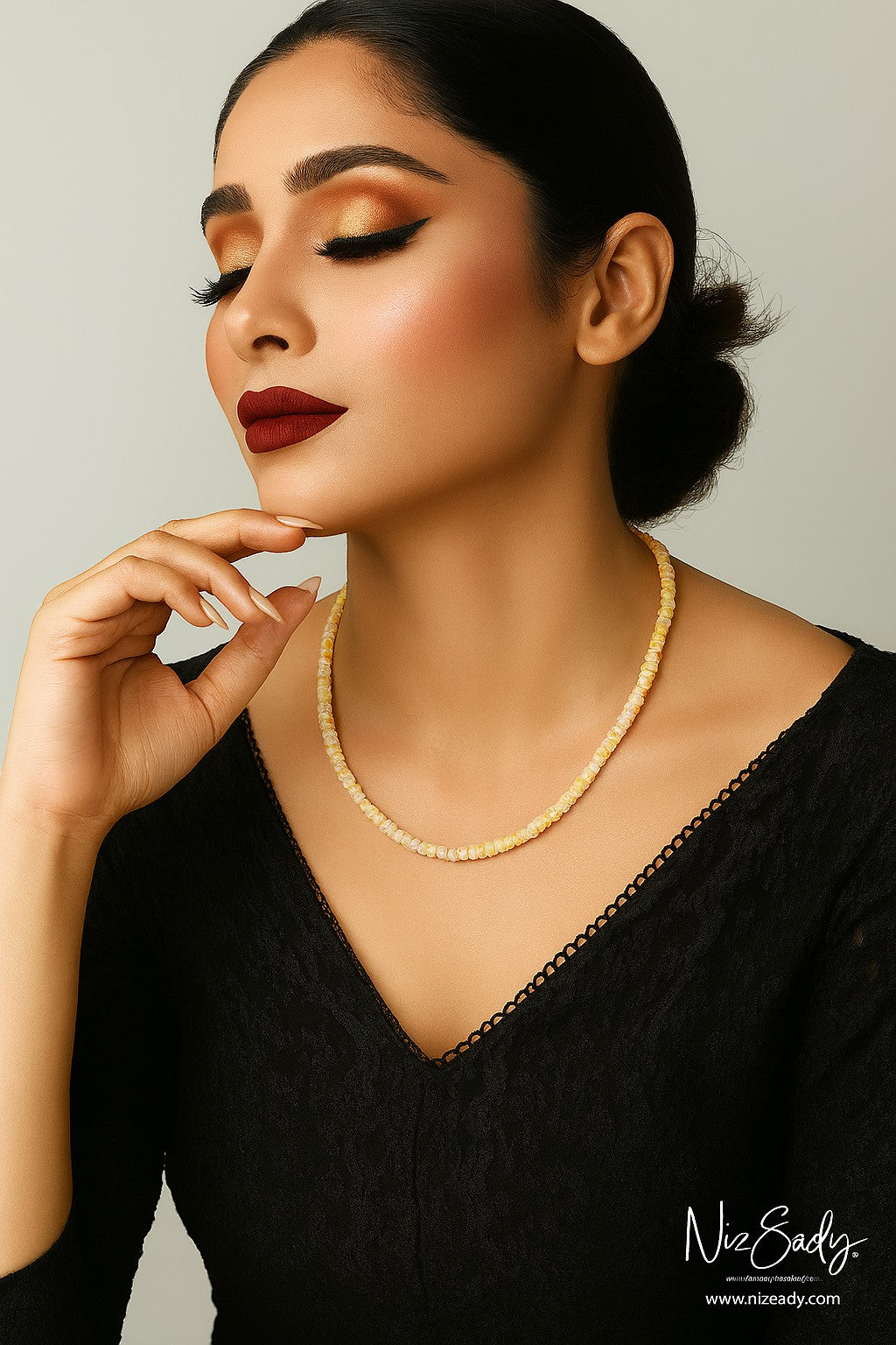 Niz & Aly Ethiopian fire opal rondelle bead necklace worn by a woman in a black top with gold eyeshadow.