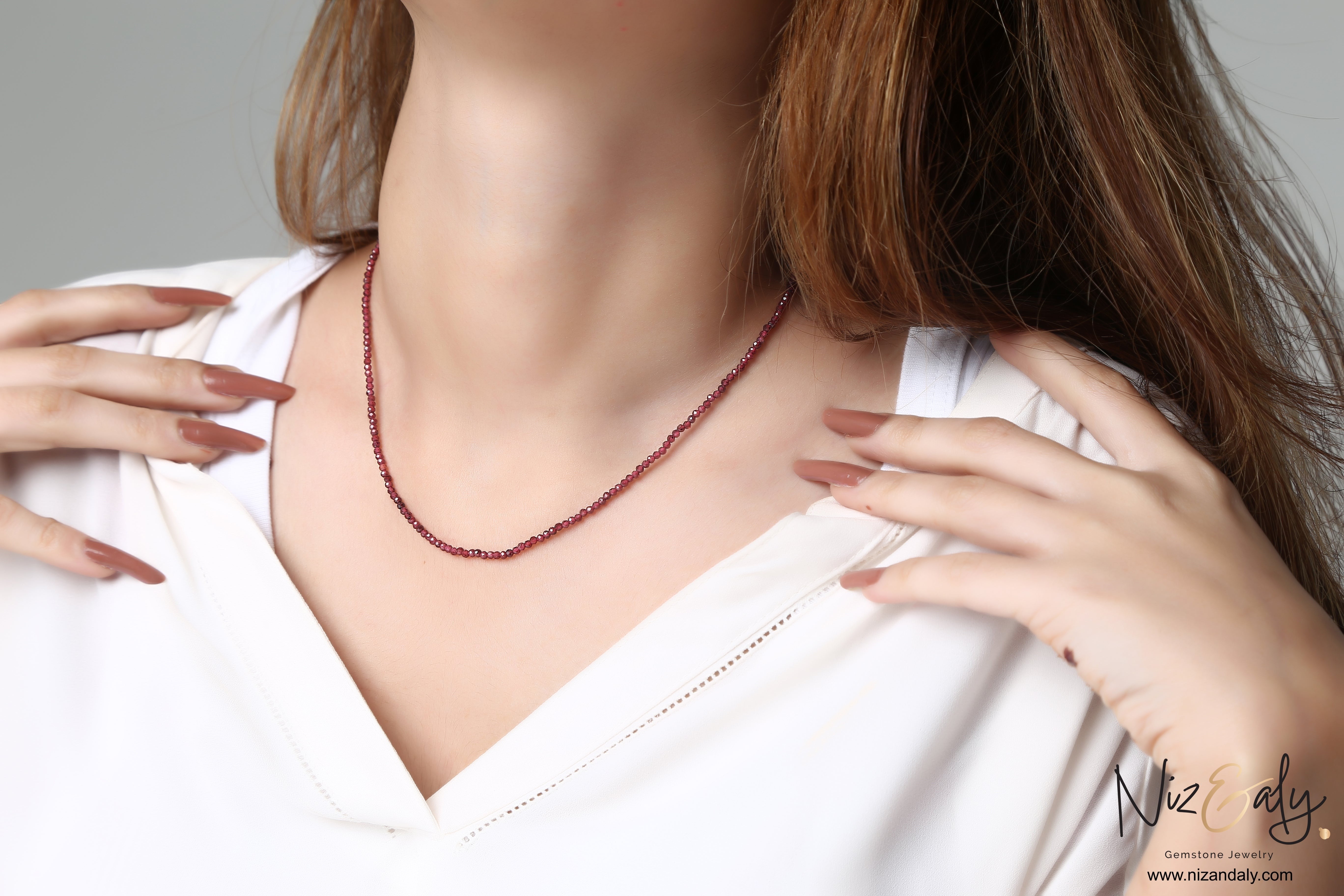 Niz & Aly dainty faceted almandine garnet bead necklace worn on a woman in a white top