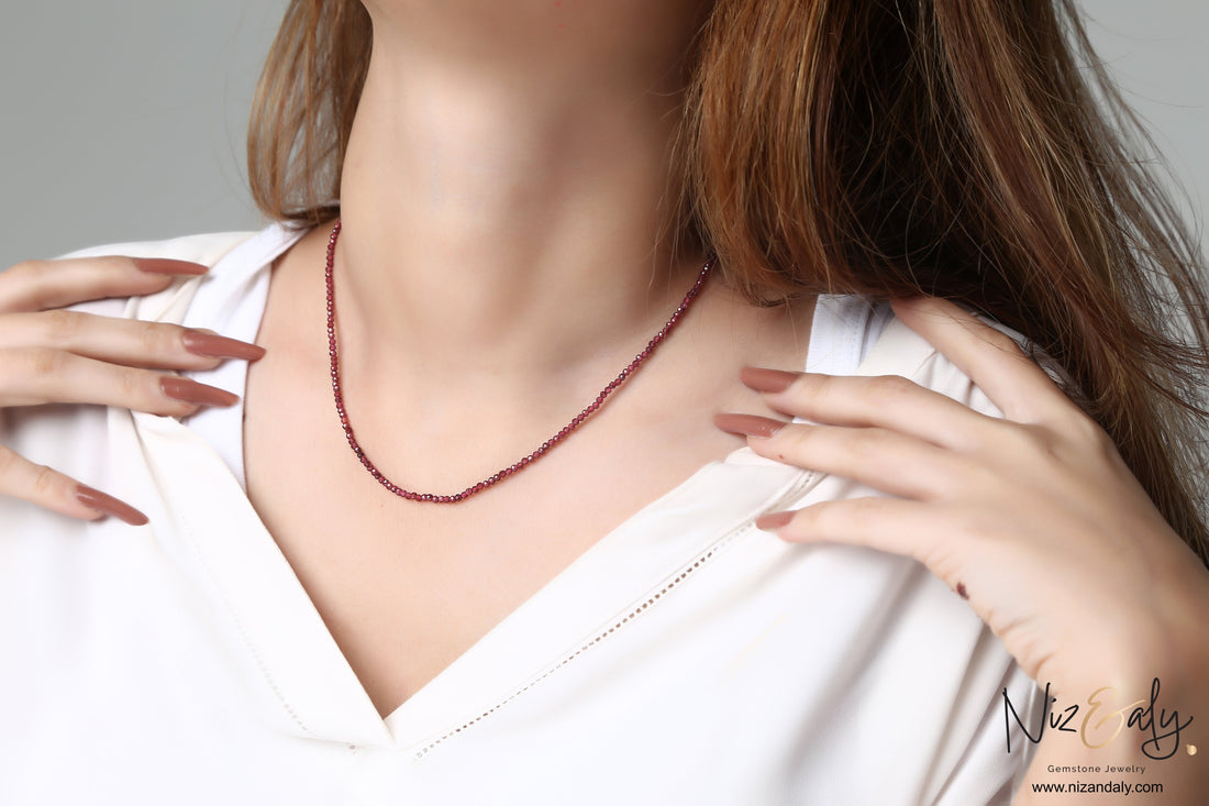 Niz & Aly dainty faceted almandine garnet bead necklace worn on a woman in a white top