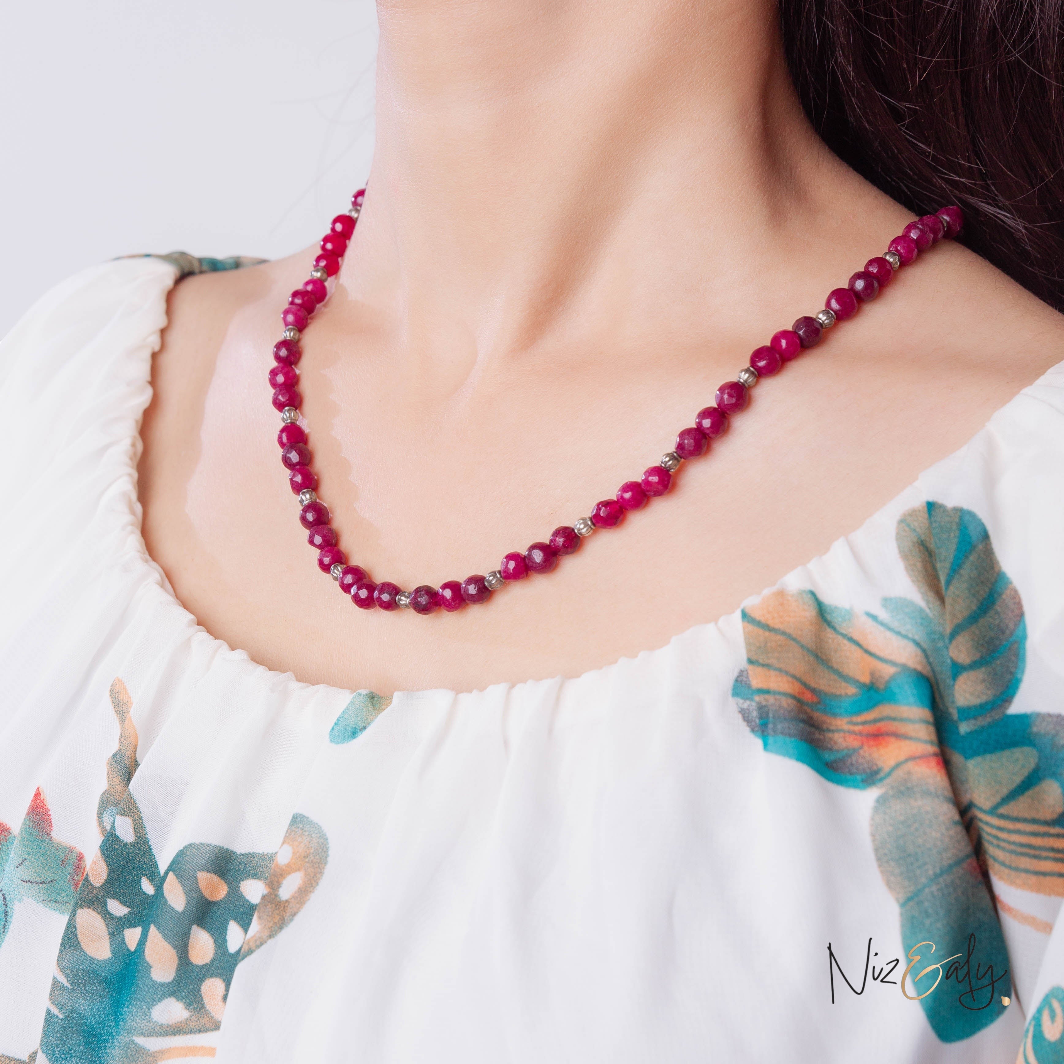 Niz & Aly faceted almandine garnet bead necklace worn on a model in a white floral top