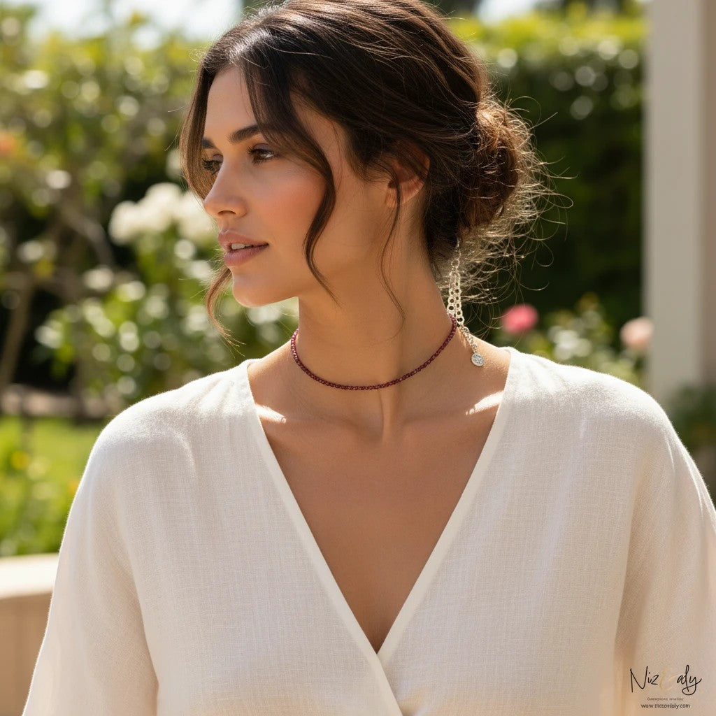 Niz & Aly dainty faceted almandine garnet bead choker necklace worn by a woman in a white top in a garden setting.
