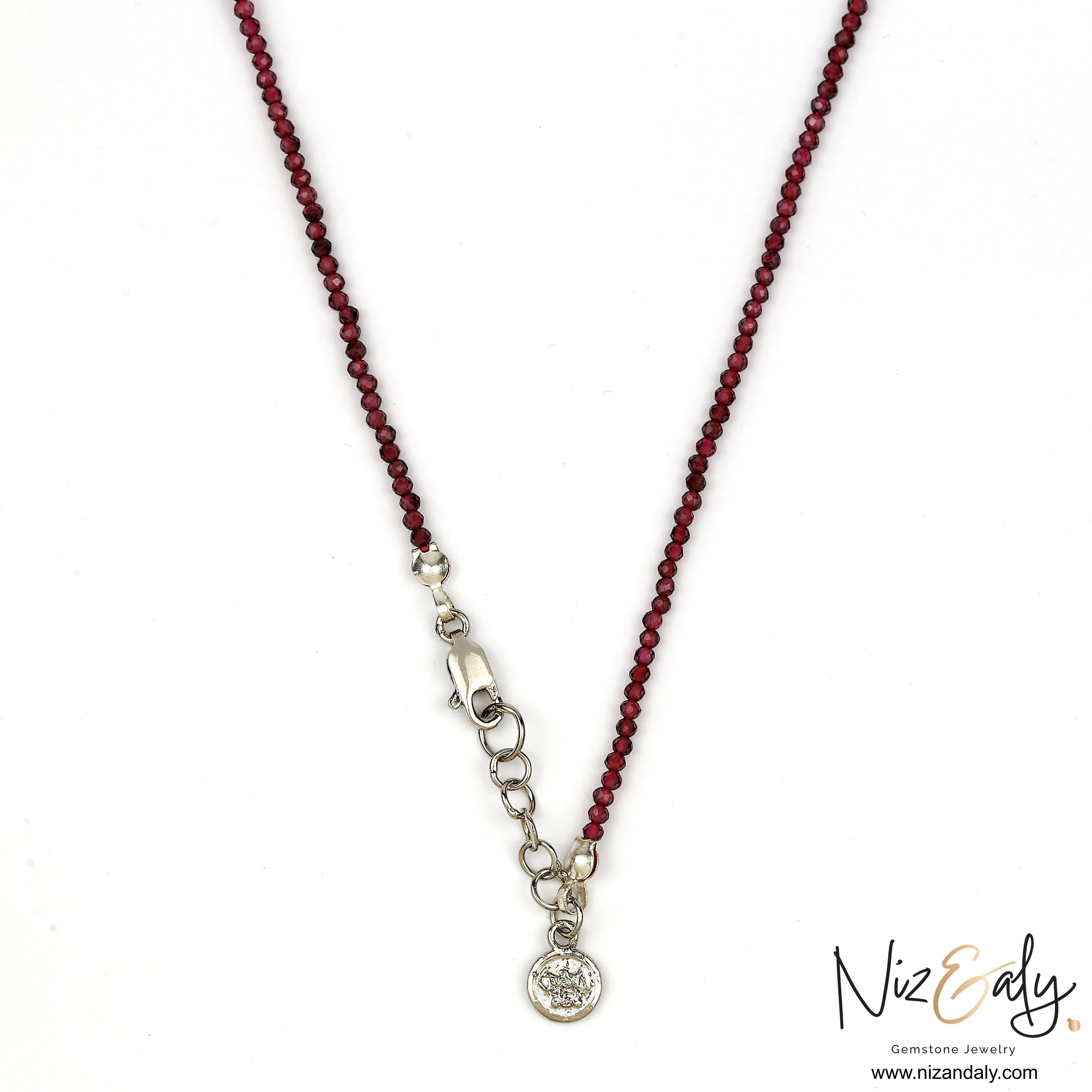 Niz & Aly dainty faceted almandine garnet bead necklace with a silver clasp and charm on a white background.