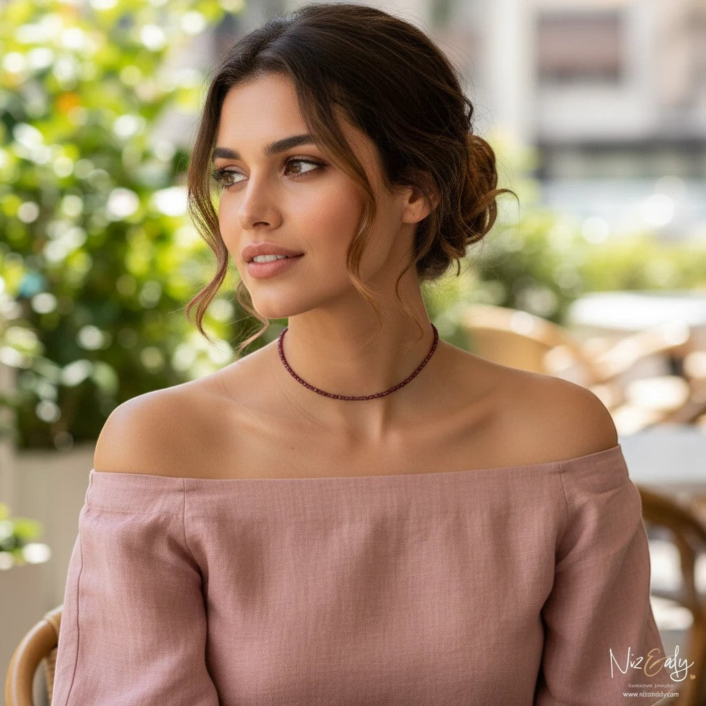 Niz & Aly dainty faceted almandine garnet bead necklace worn by a woman in a pink off-shoulder top