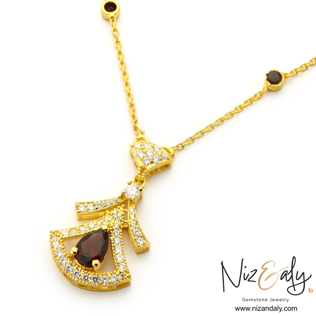 Niz & Aly Midnight Grace gold pendant necklace featuring a deep red garnet, clear stones, and dark gemstone accents.