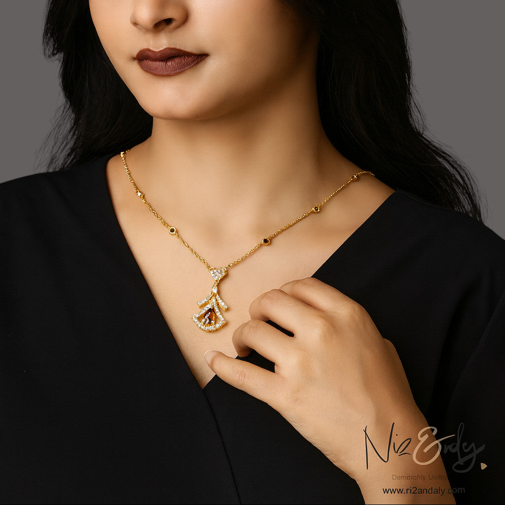 Niz & Aly Midnight Grace gold pendant necklace featuring a deep red garnet, clear stones, and dark gemstone accents.