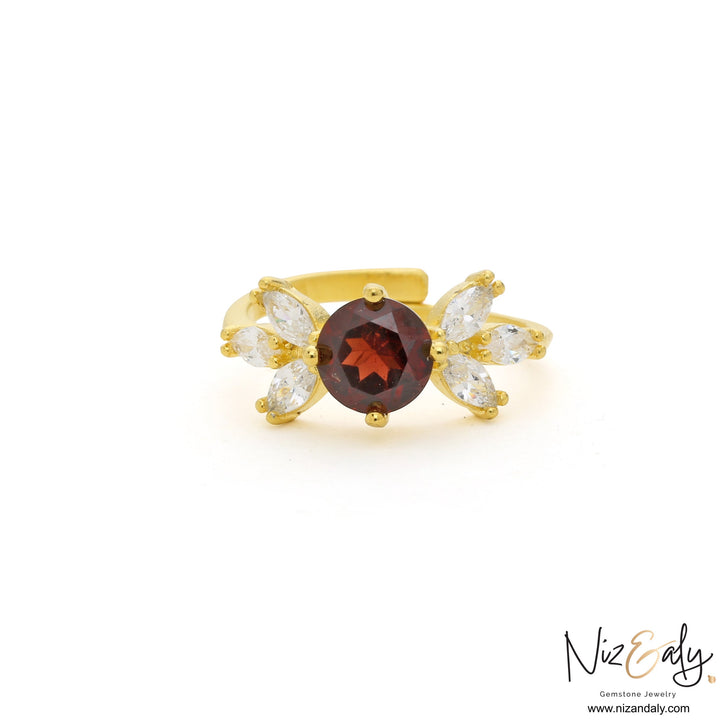 Niz & Aly gold ring featuring a round natural garnet center stone flanked by marquise-cut white crystals