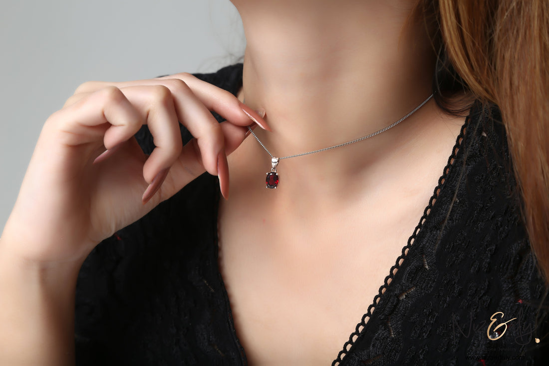Niz & Aly garnet locket pendant on a delicate silver chain worn by a woman in a black dress
