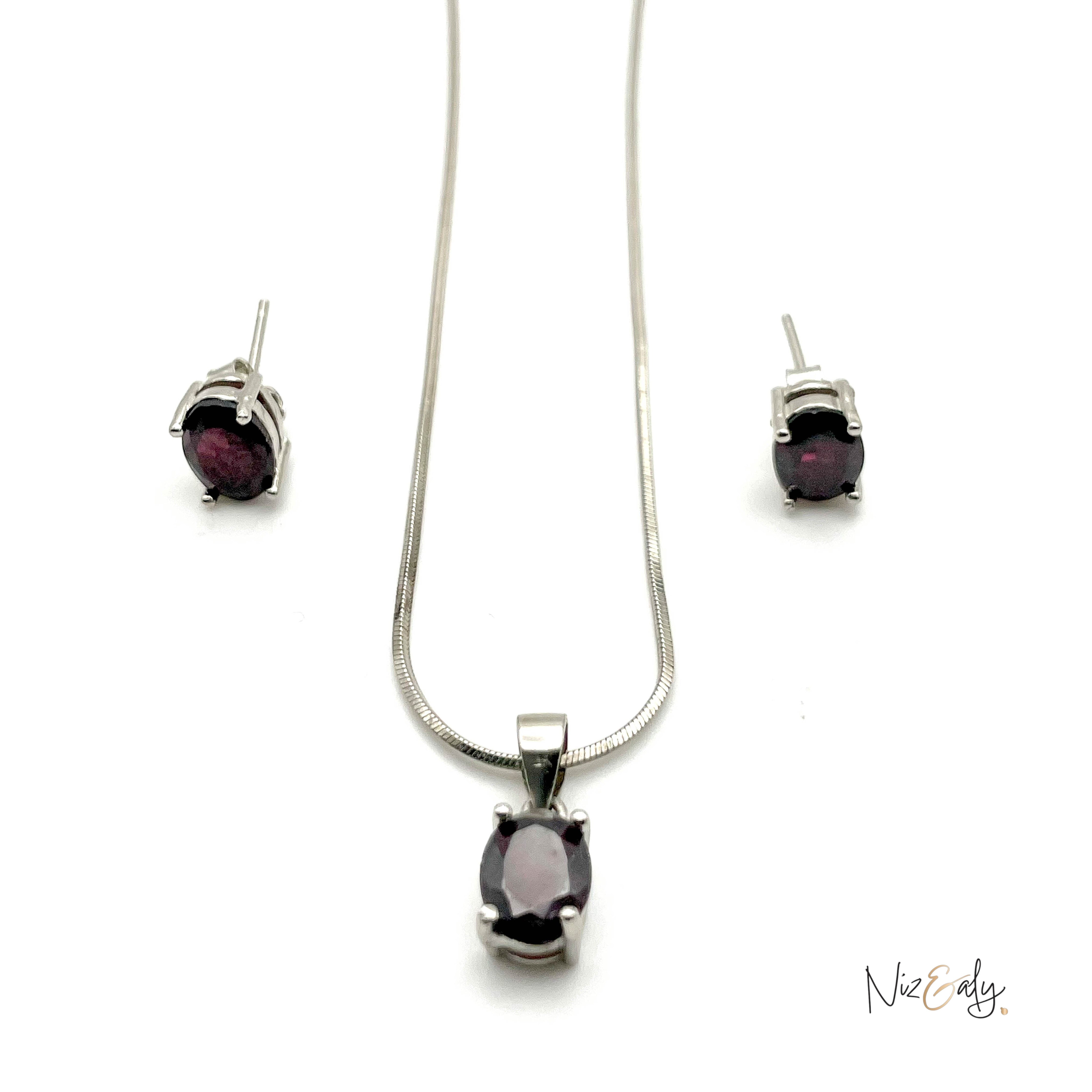 Niz & Aly garnet locket necklace and matching stud earrings set in silver with deep red oval gemstones.