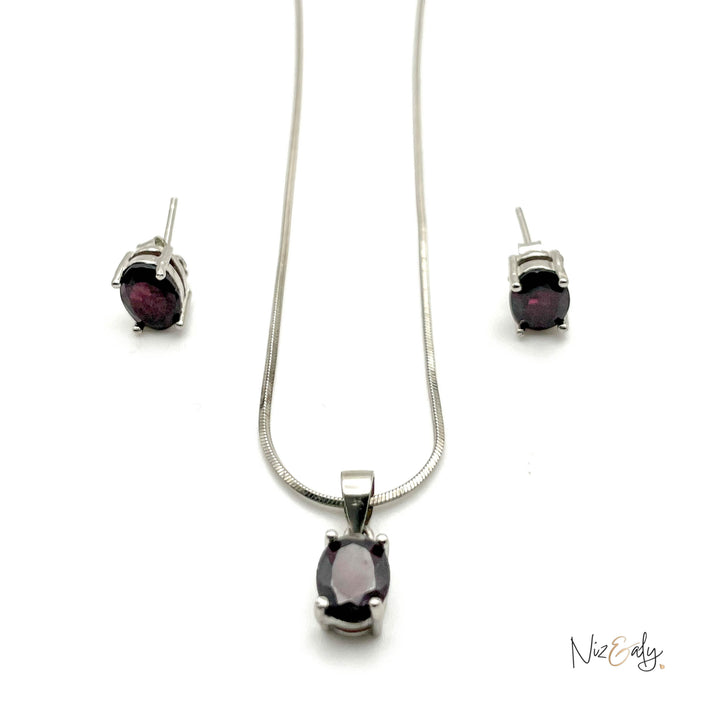 Niz & Aly garnet locket necklace and matching stud earrings set in silver with deep red oval gemstones.