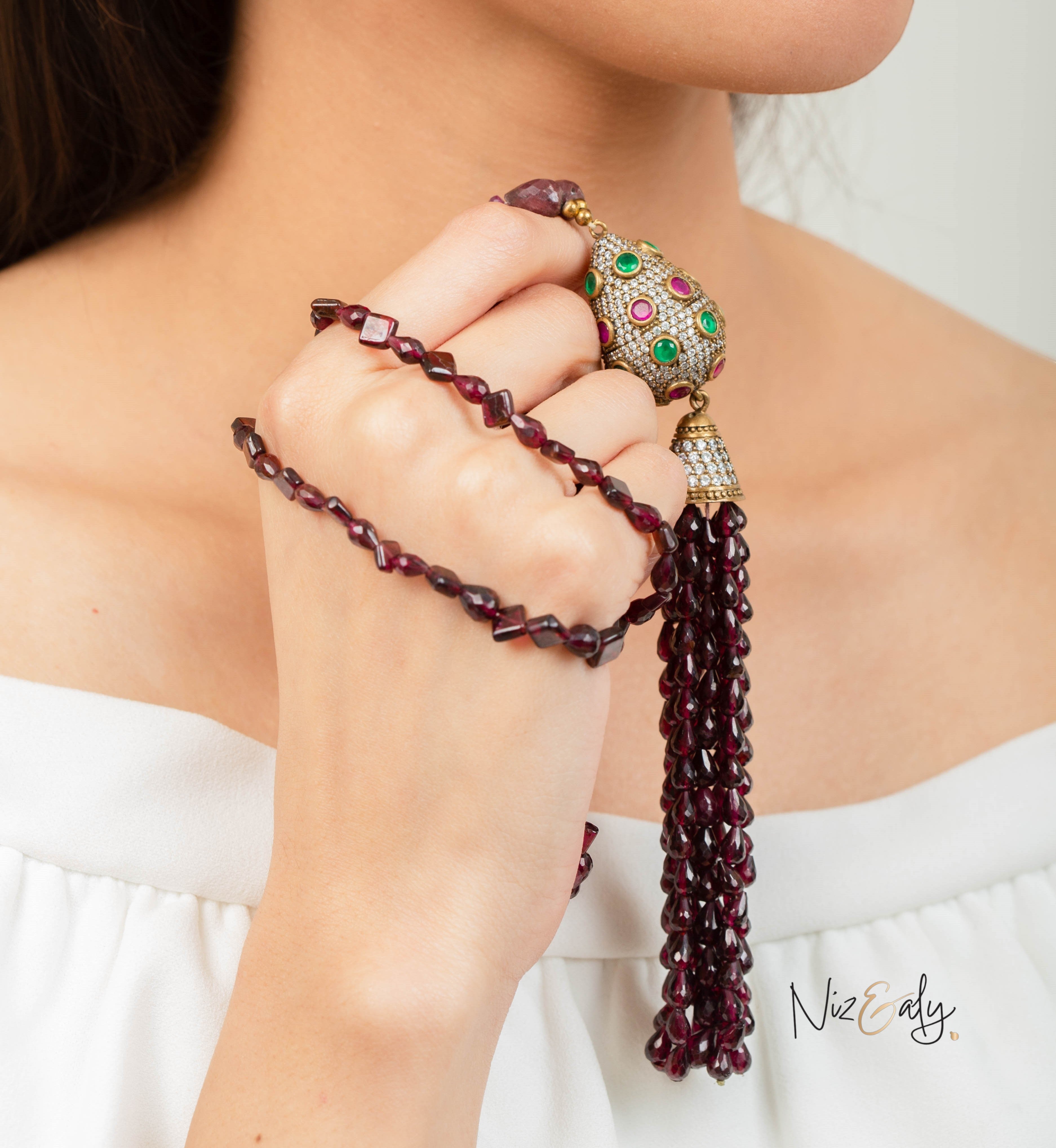 Niz & Aly Mozambique Almandine garnet tassel necklace featuring ruby and emerald accents on a model