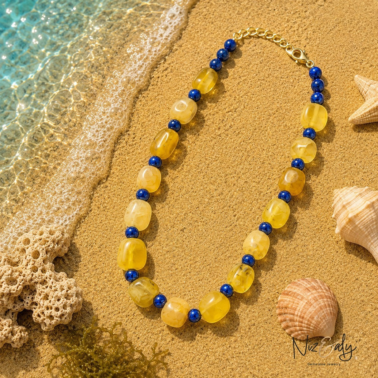 Niz & Aly necklace featuring yellow and blue semi-precious gemstone beads on a sandy beach with seashells.