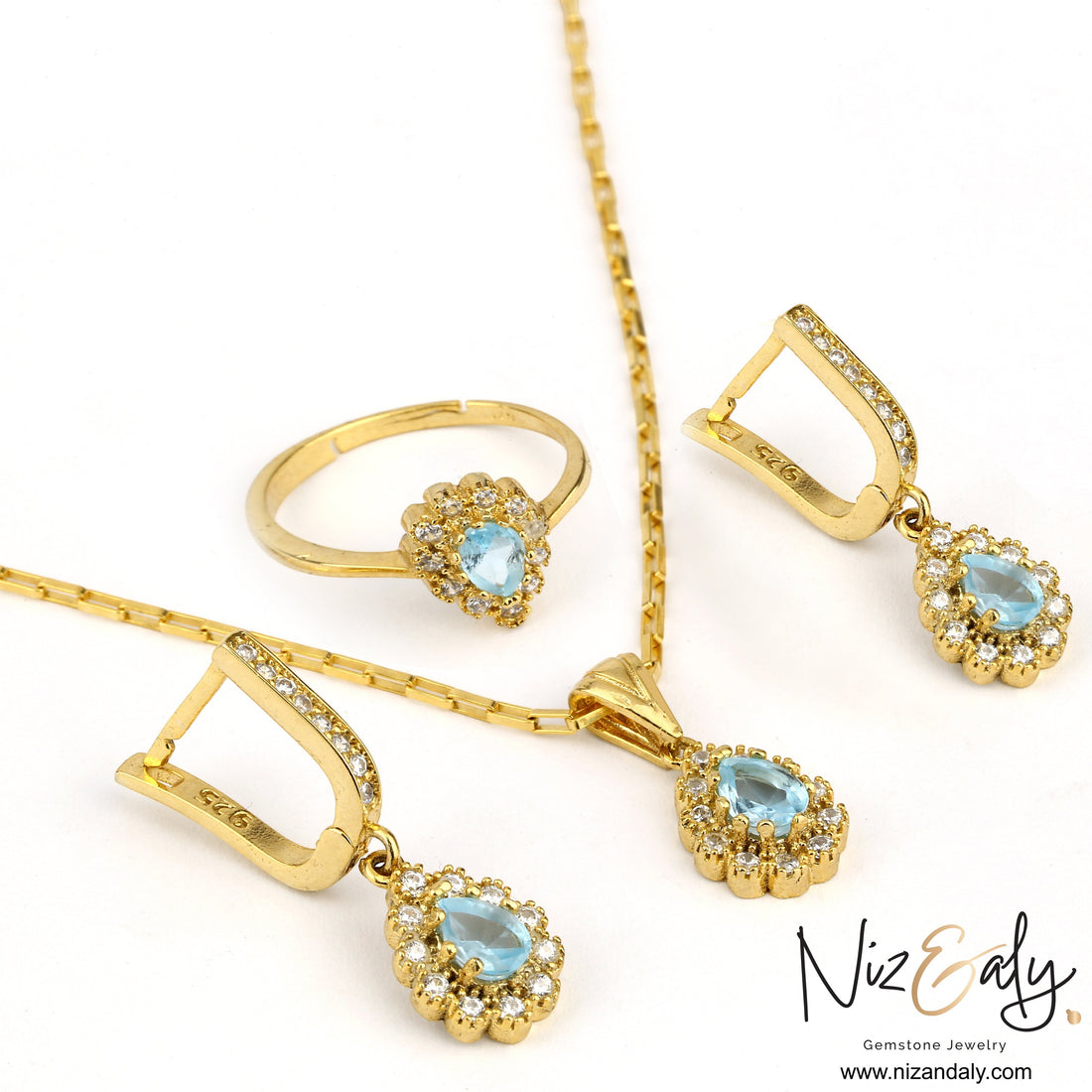 Niz & Aly gold plated jewelry set featuring pear-shaped blue topaz stones surrounded by sparkling white crystals.