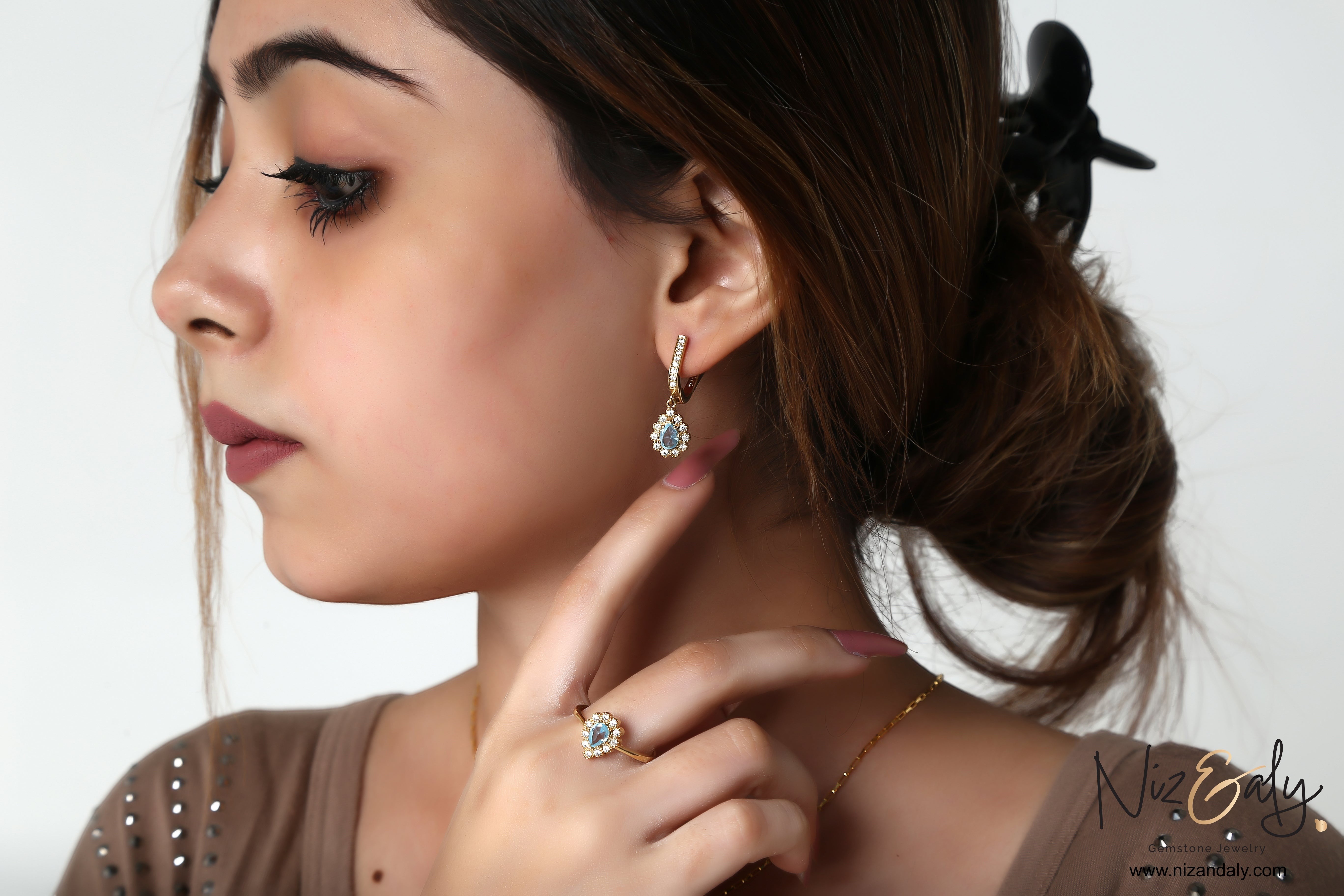 Niz & Aly gold-plated pear-shaped blue topaz earring and ring set worn by a woman