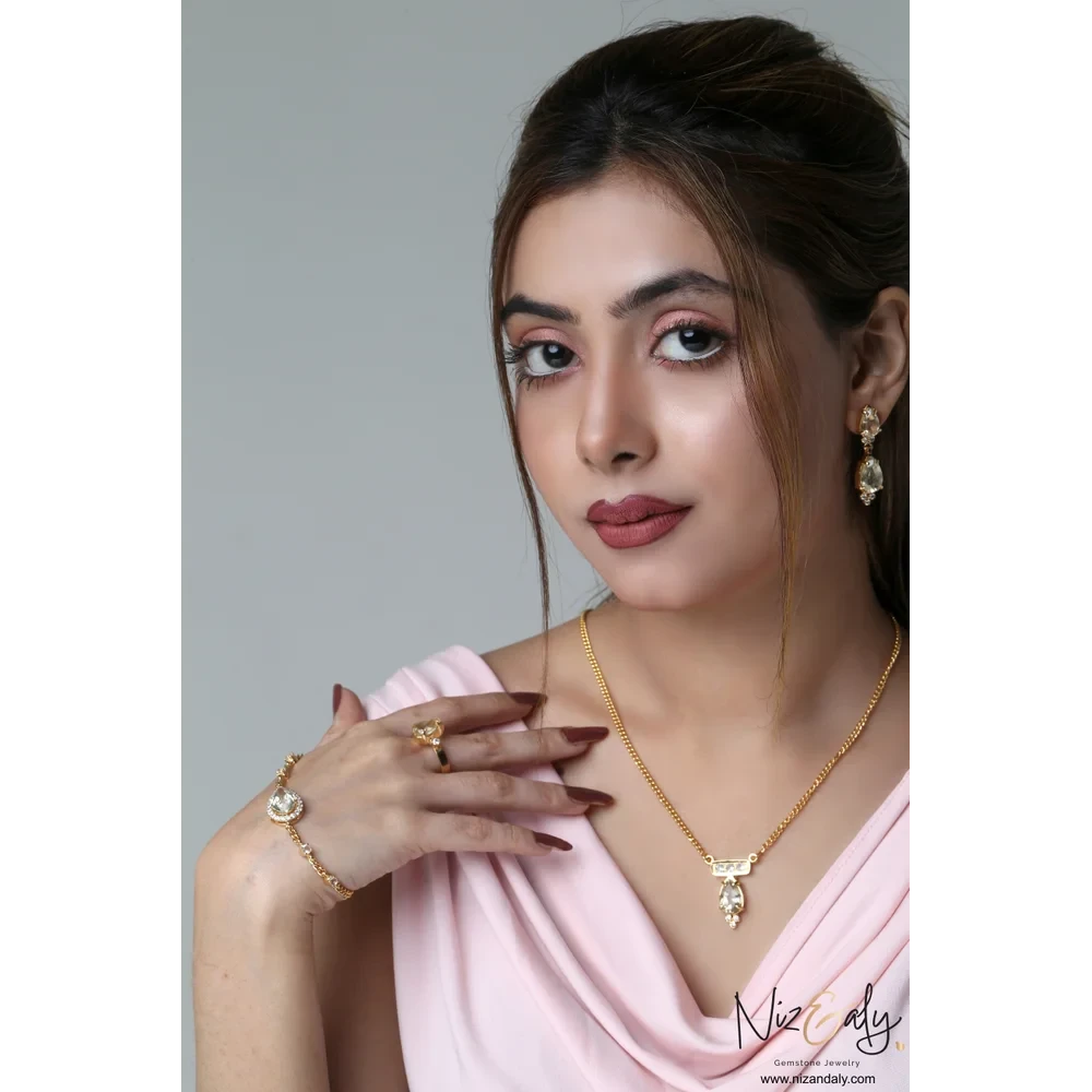 Niz & Aly gold-plated sterling silver jewelry set with faceted teardrop clear quartz worn by a woman in pink