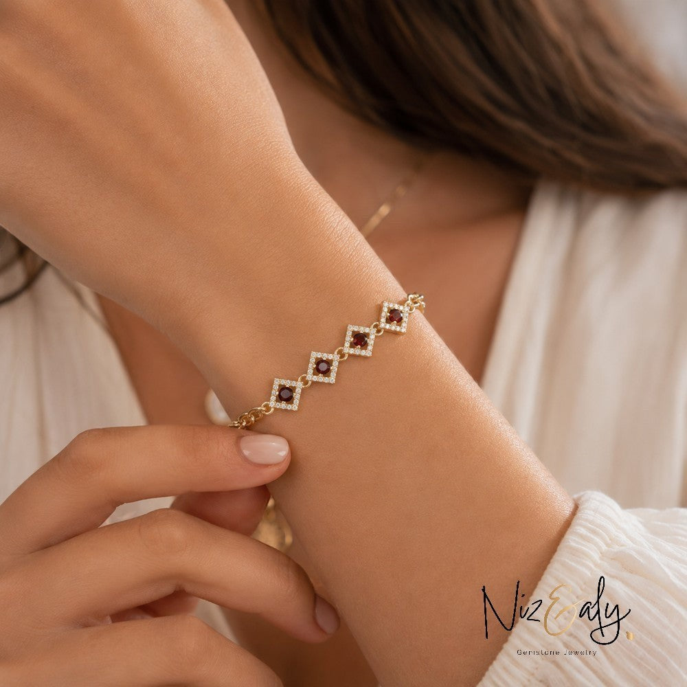 Niz & Aly 14K gold-plated silver bracelet featuring diamond-shaped links with red garnet stones and a sparkling halo.