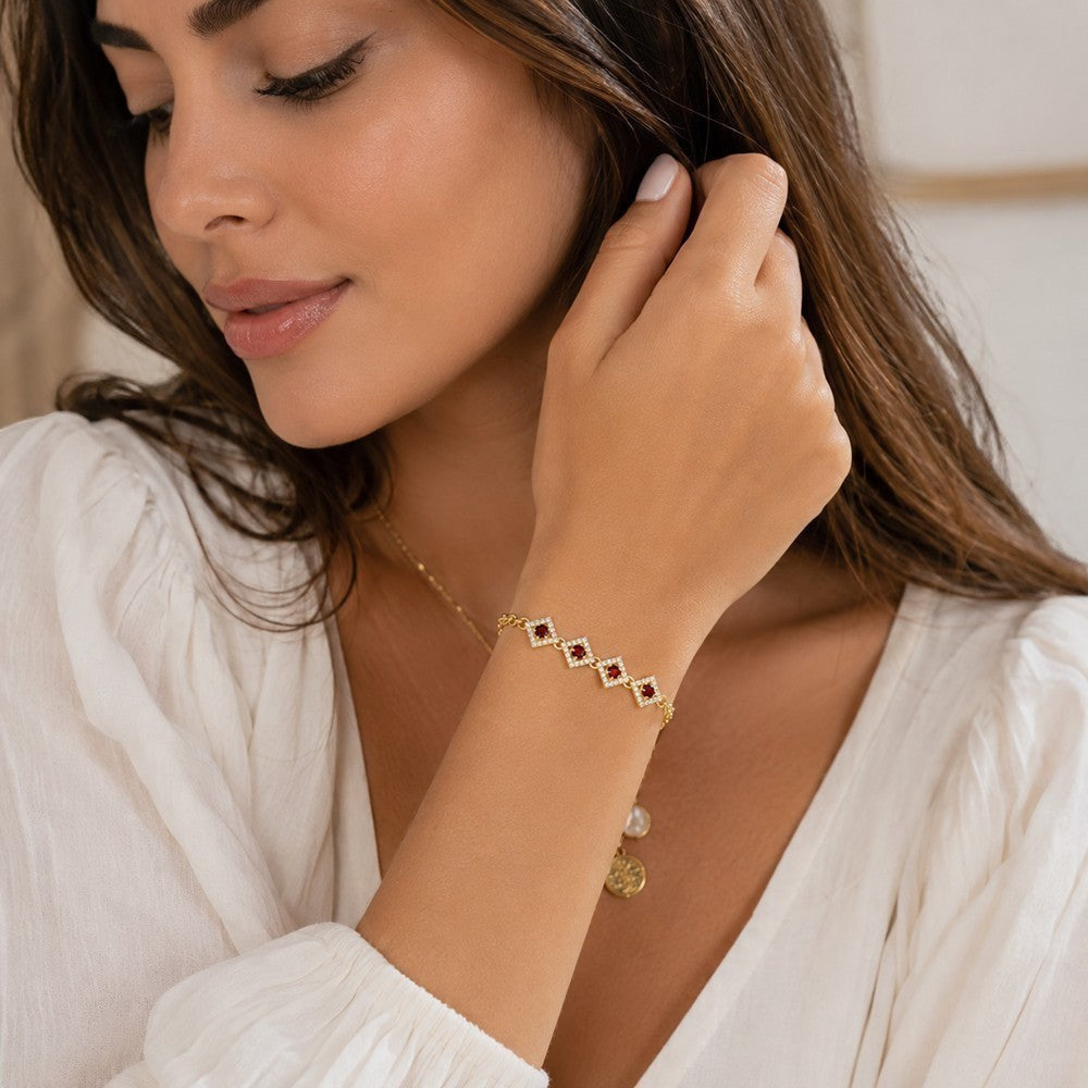 Niz & Aly 14K gold-plated silver bracelet featuring diamond-shaped links with red garnet stones and halo accents.