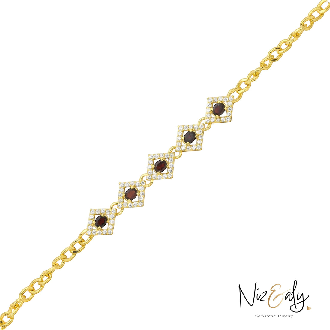 Niz & Aly 14K gold-plated silver bracelet featuring diamond-shaped links with deep red garnet stones and crystal halos.