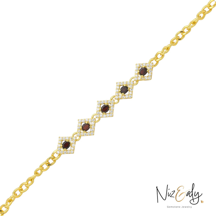 Niz & Aly 14K gold-plated silver bracelet featuring diamond-shaped links with deep red garnet stones and crystal halos.