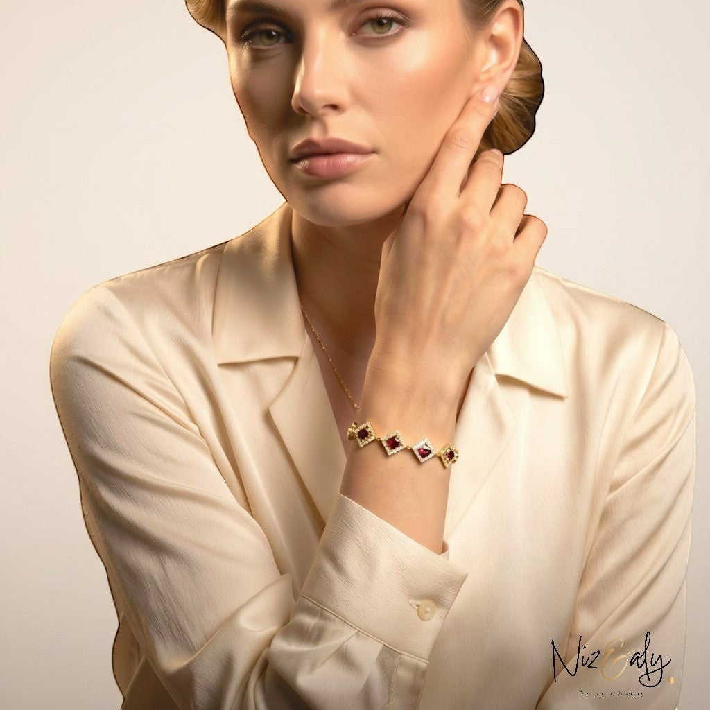 Niz & Aly 14K gold-plated silver bracelet featuring diamond-shaped links with red garnet stones on a woman's wrist.