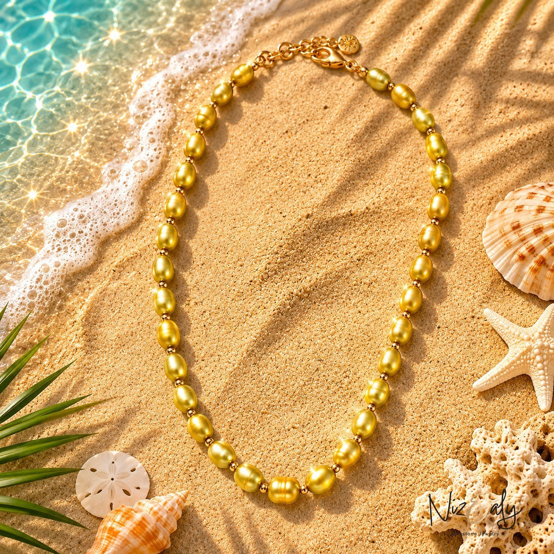 Niz & Aly gold gemstone bead necklace on a sandy beach with seashells and palm shadows for a summer coastal look