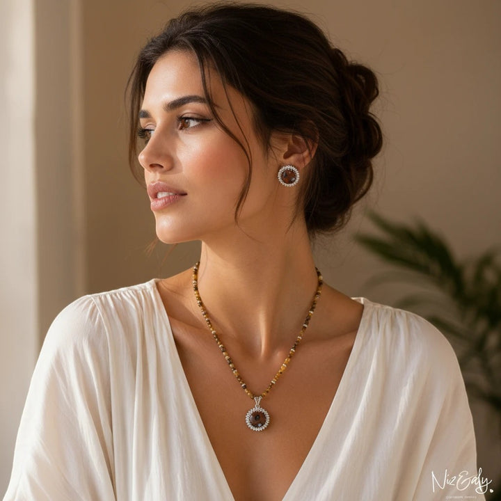 Niz & Aly gold orgonite pendant necklace with tiger's eye beads and matching earrings worn by a woman.
