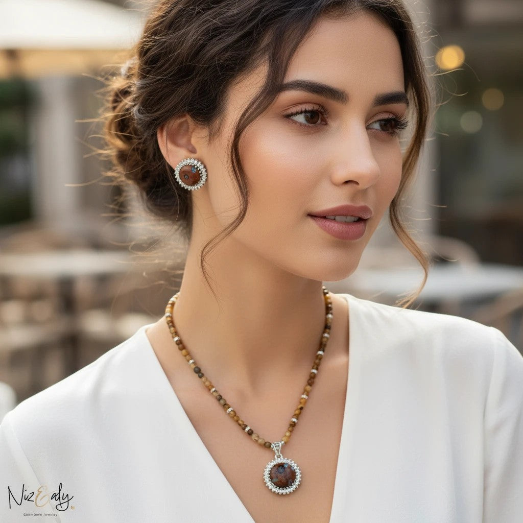 Niz & Aly gold orgonite pendant necklace with tiger's eye beads and matching earrings worn by a woman.