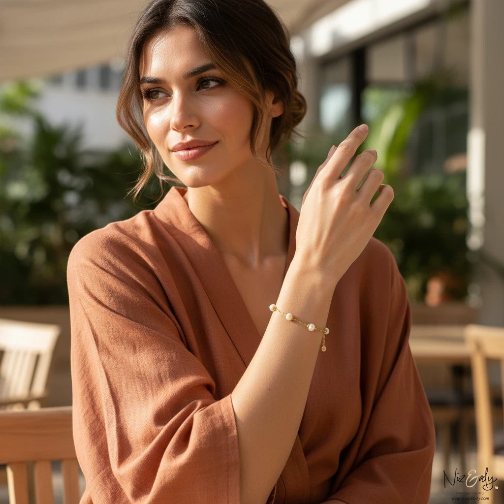 Niz & Aly gold-plated 925 silver bracelet with white freshwater pearls worn by a woman in a terracotta linen top