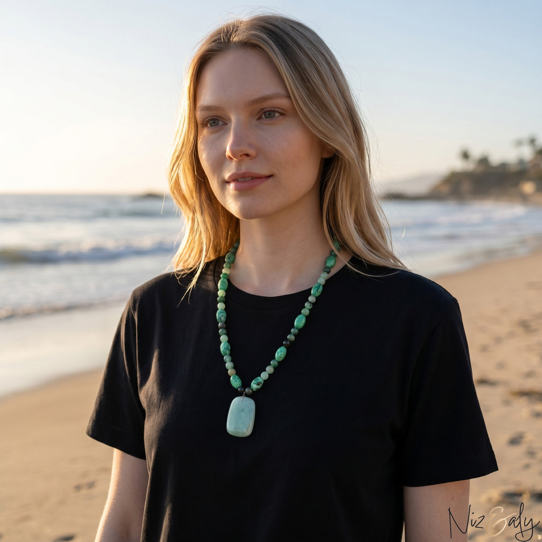 Niz & Aly green aventurine and agate beaded pendant necklace worn by a woman on a sunny beach at sunset