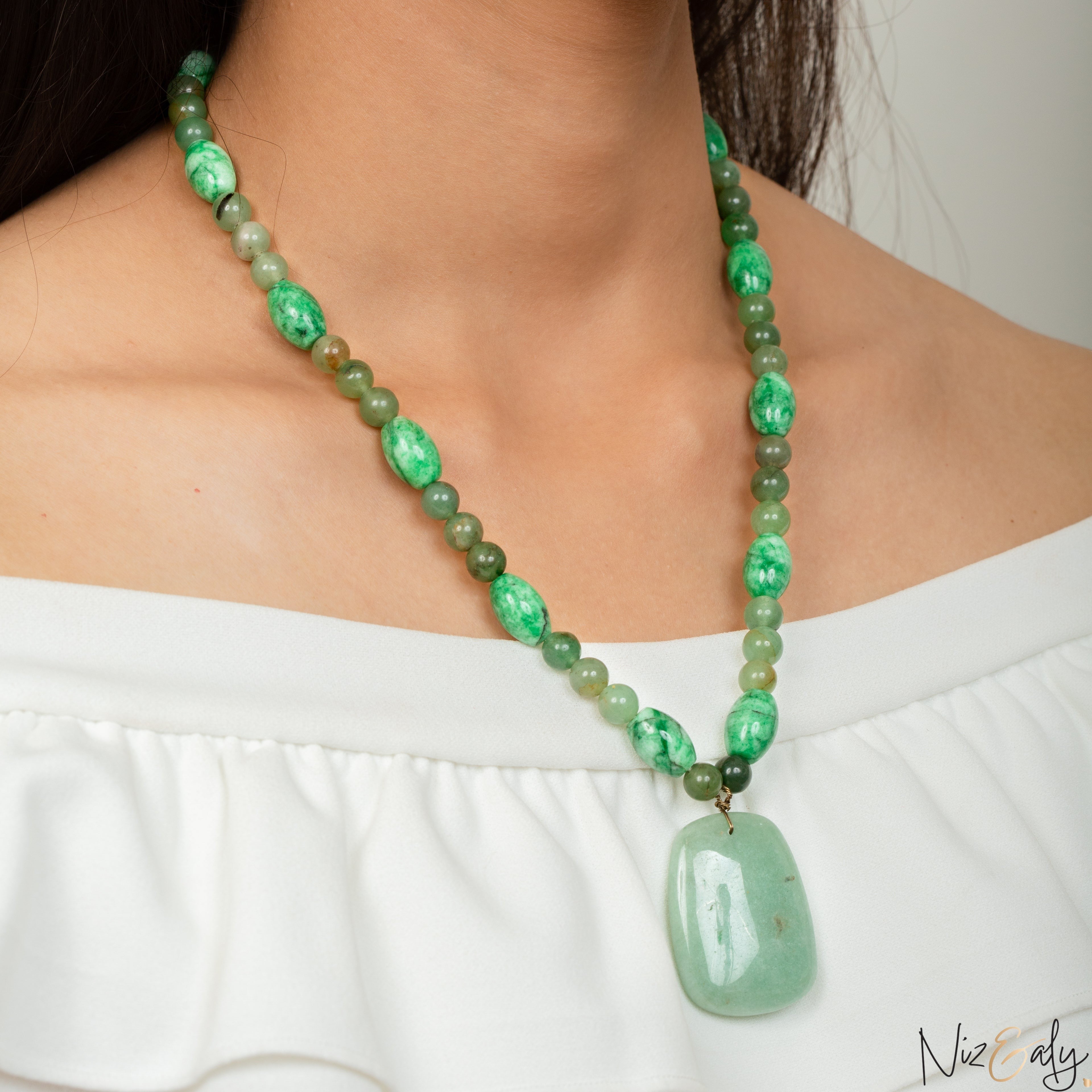 Niz & Aly green aventurine and agate beaded necklace with a large polished pendant worn by a woman in a white top.