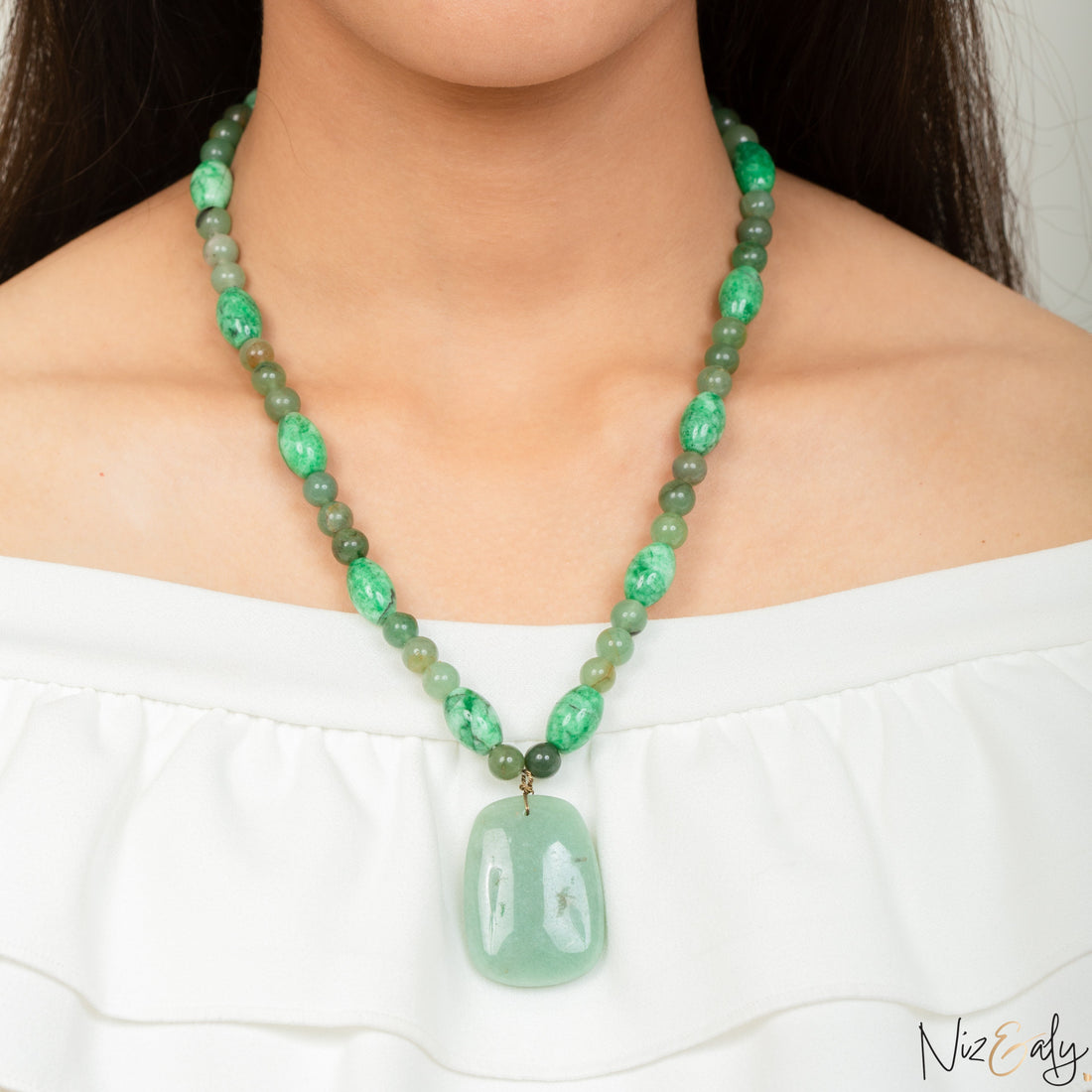 Niz & Aly green aventurine and agate beaded necklace with a large smooth pendant worn on a model in a white top.