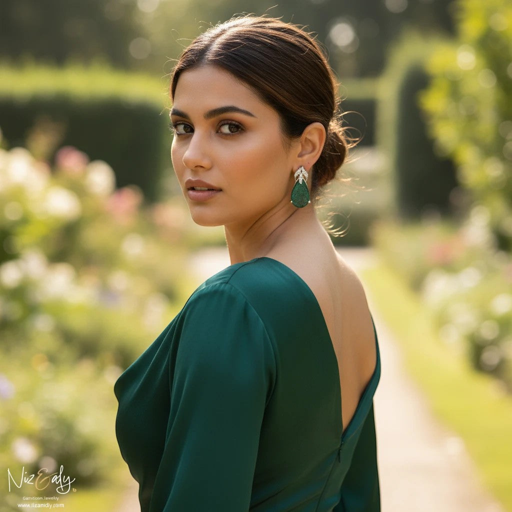 Niz & Aly pear-shaped green chrysocolla stud earrings in sterling silver worn by a woman in a green dress outdoors.