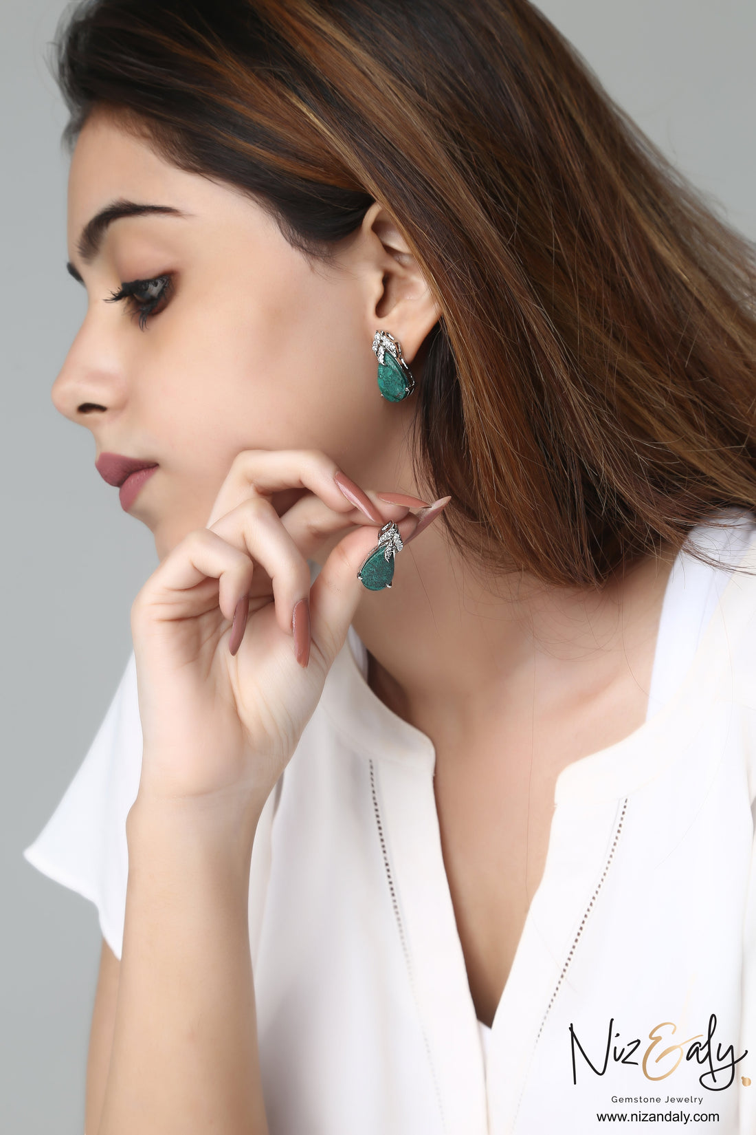 Niz & Aly pear-shaped green chrysocolla stud earrings in sterling silver worn by a woman with long brown hair.