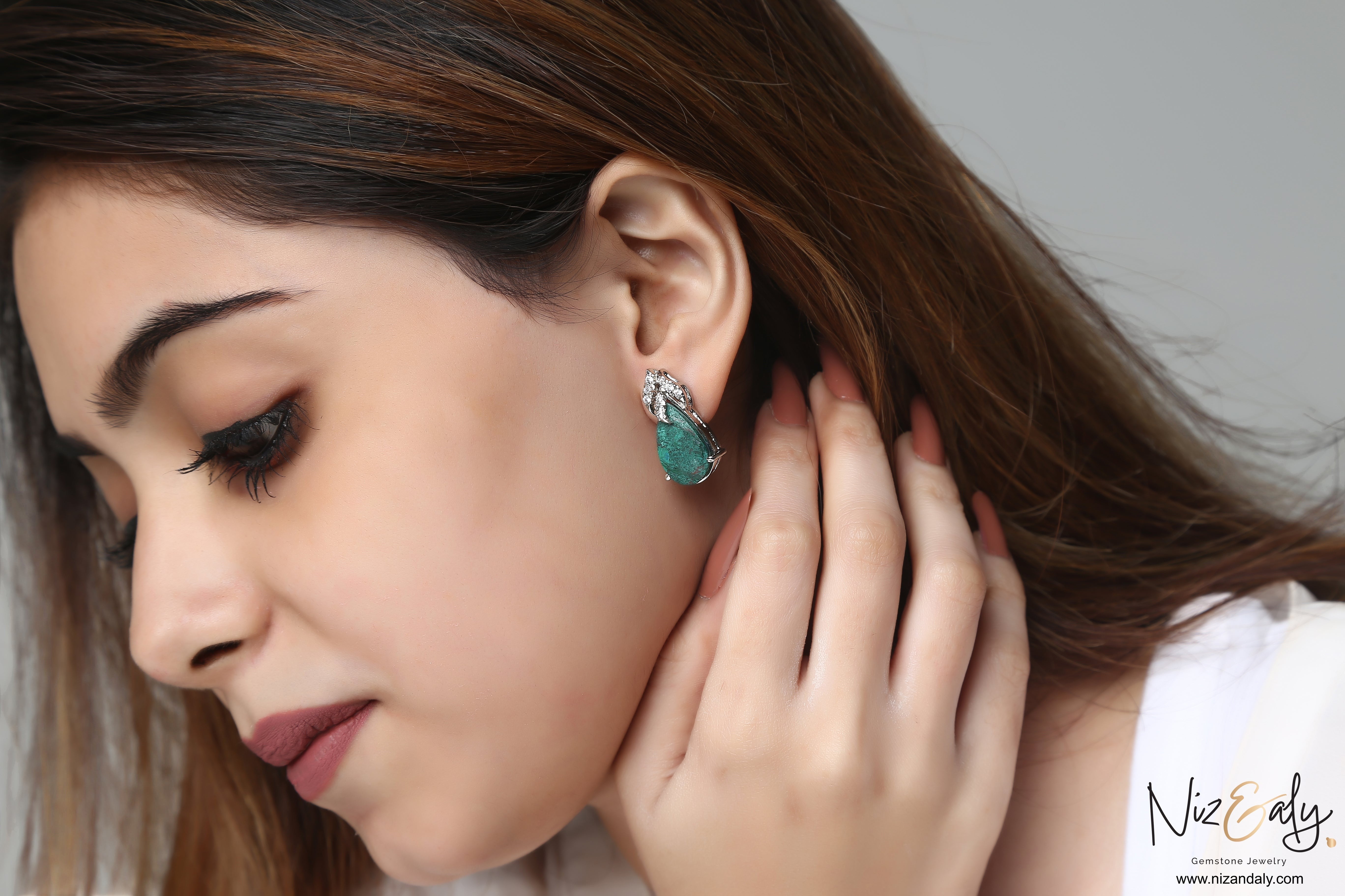 Niz & Aly pear-shaped green chrysocolla stud earrings in sterling silver worn by a woman with long brown hair
