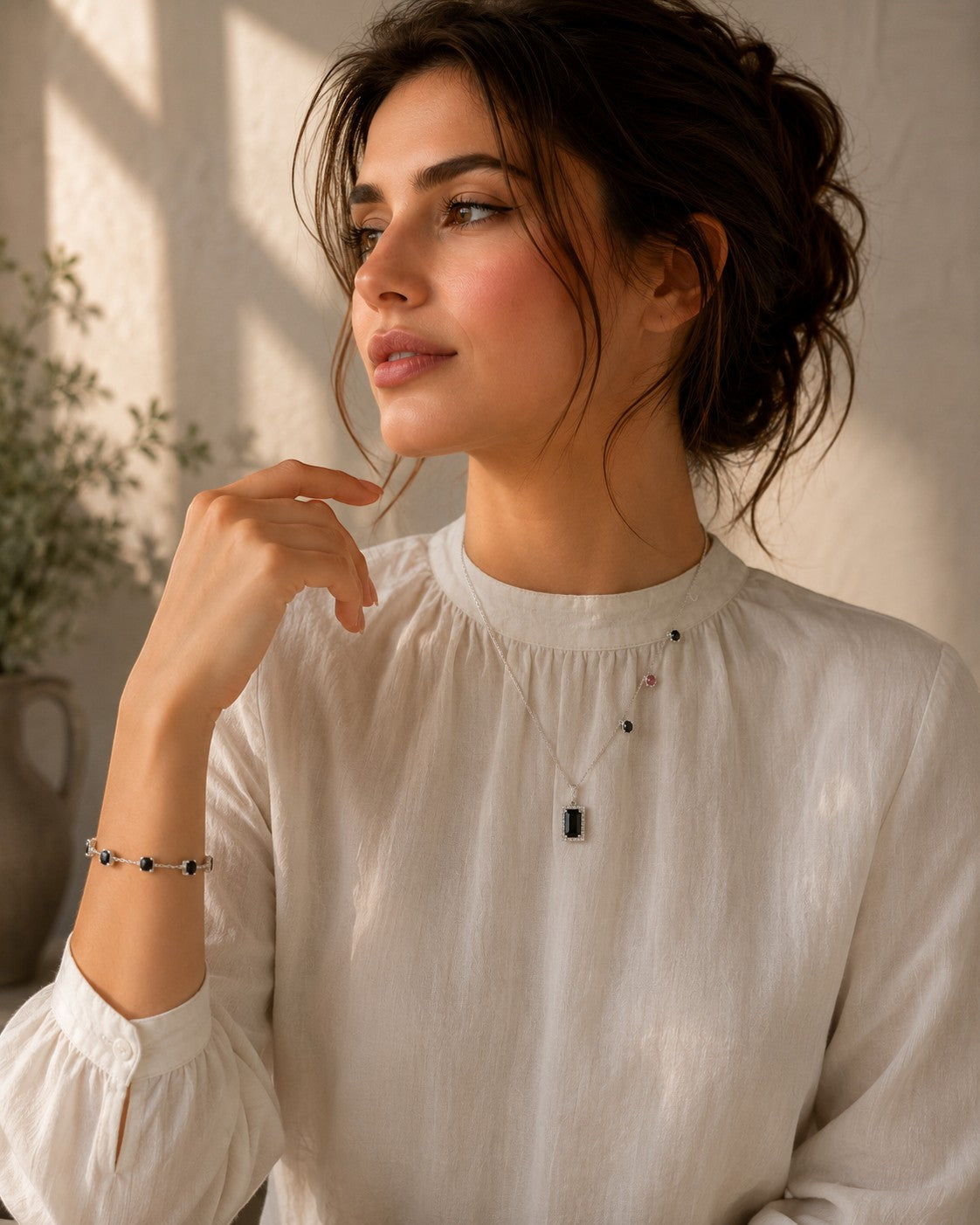 Niz & Aly green tourmaline pendant necklace on a woman wearing a white blouse, featuring a delicate silver chain.