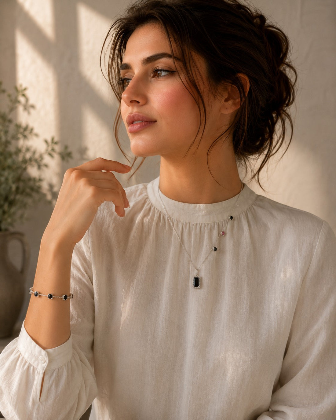Niz & Aly green tourmaline pendant necklace on a woman wearing a white blouse, featuring a delicate silver chain.