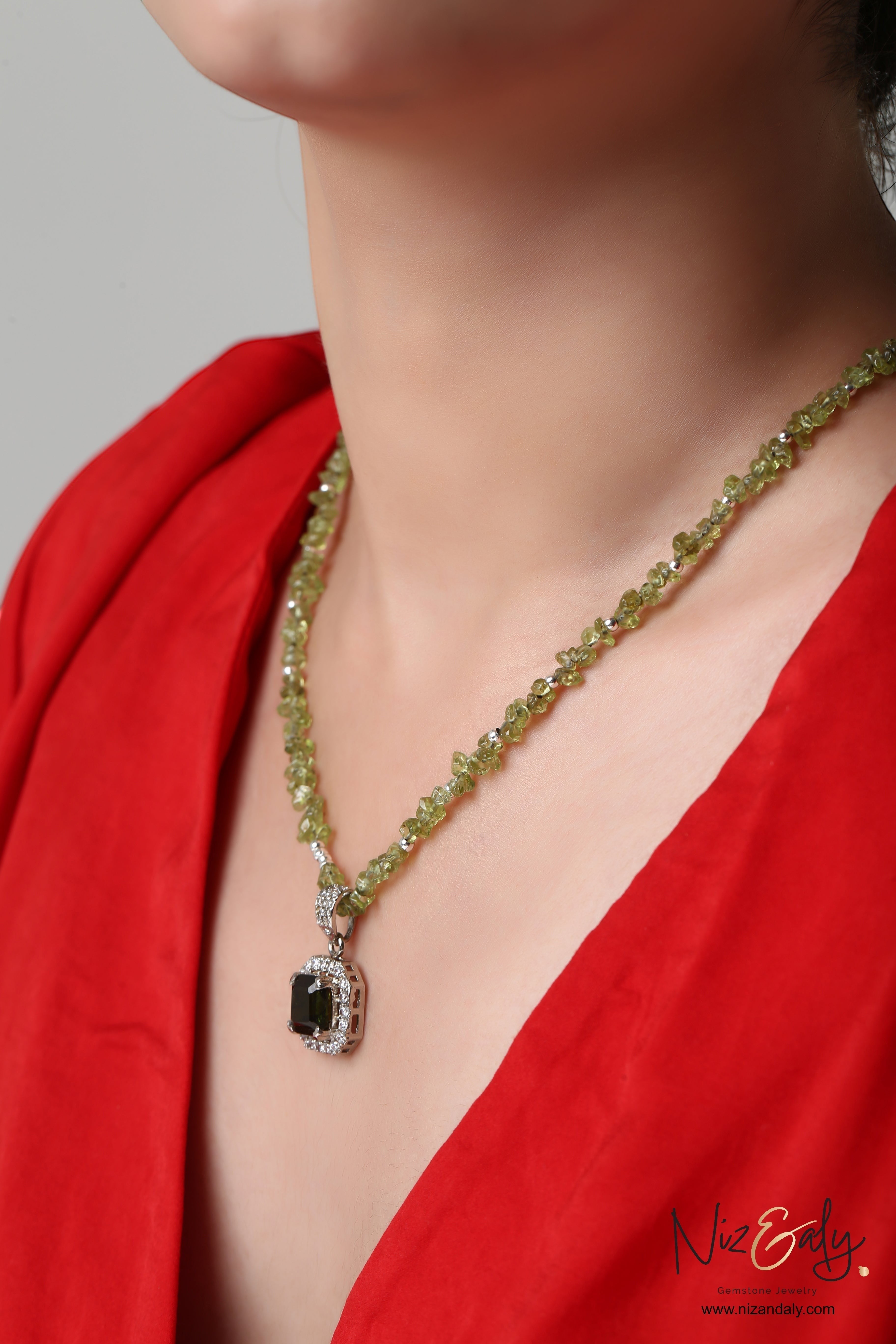 Niz & Aly green tourmaline pendant on a delicate peridot gemstone chain worn by a woman in a red top