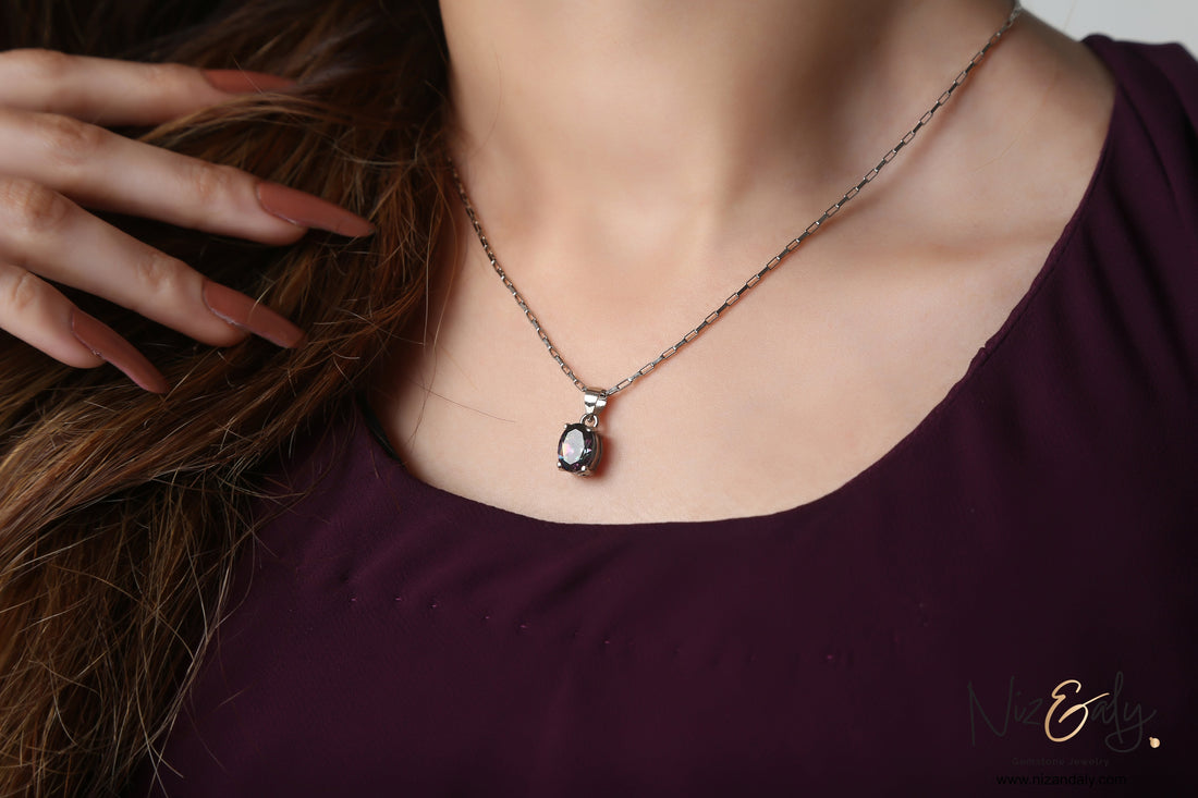 Niz & Aly solitaire pendant featuring a deep blue-violet iolite gemstone on a delicate silver chain worn by a woman.