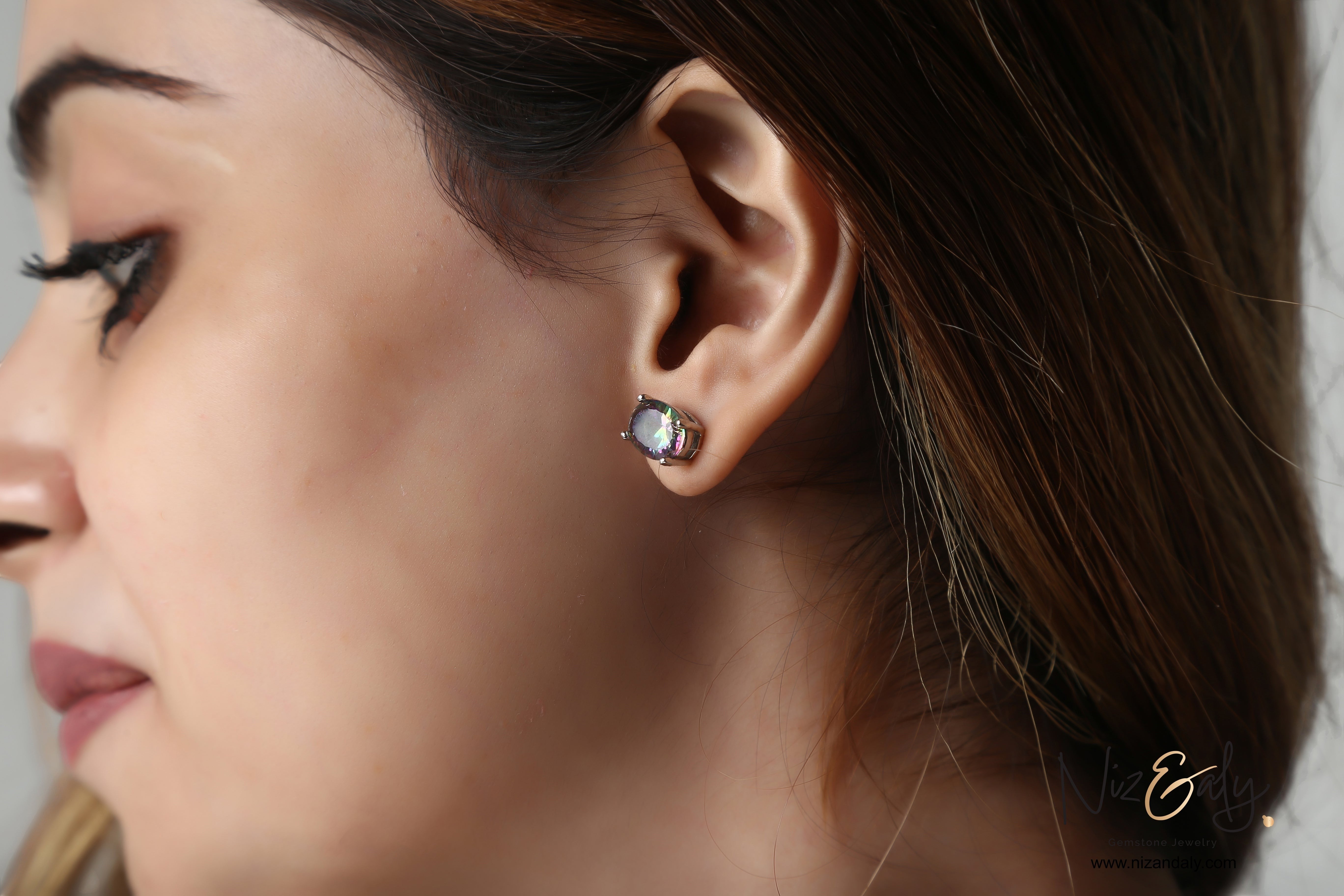 Niz & Aly iolite solitaire stud earring worn on a model, featuring a deep blue-violet gemstone in a silver setting.